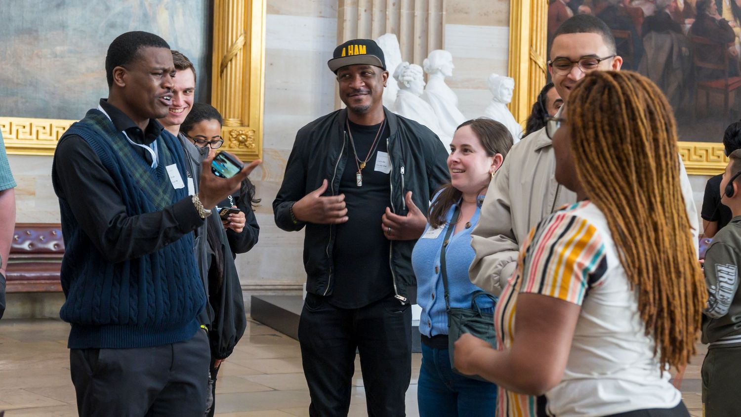 Group of people having animated conversation in ornate government building rotunda.