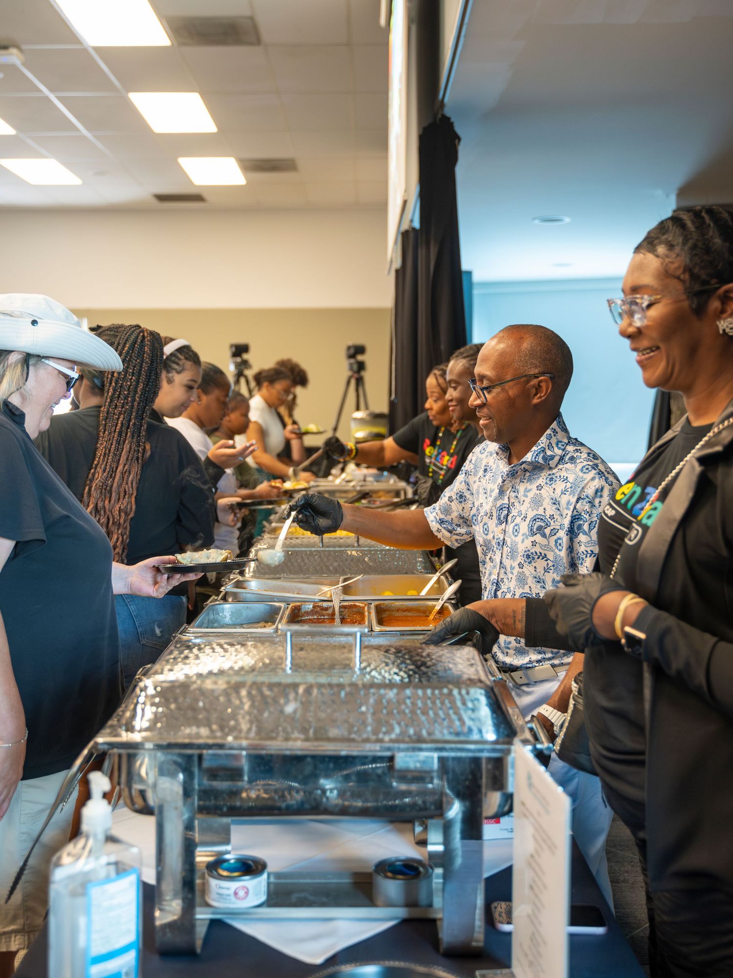 Catering staff serving food at a buffet line during a graduation celebration event.