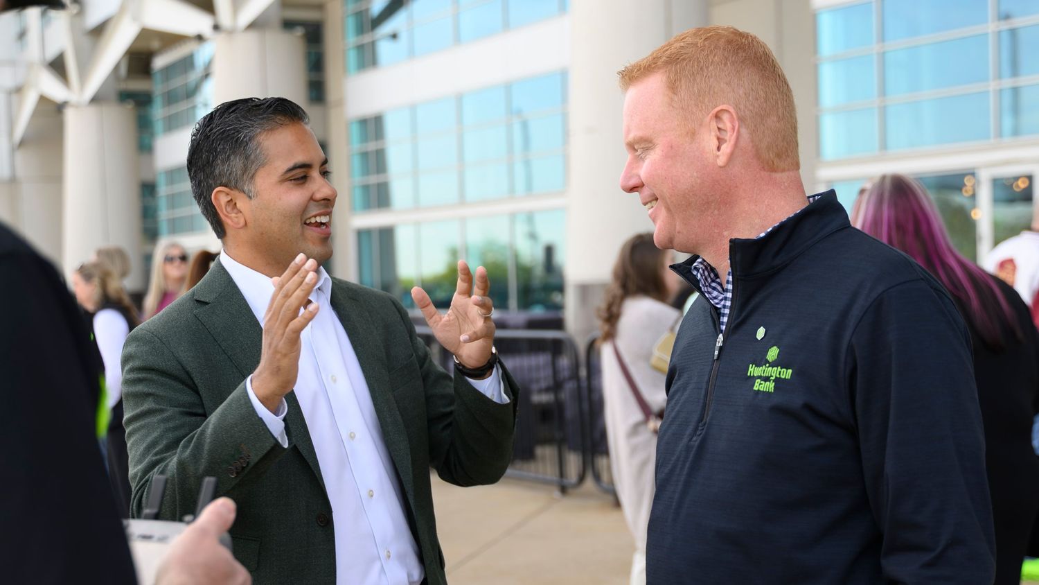 Two men smiling and conversing outdoors at a professional networking event.