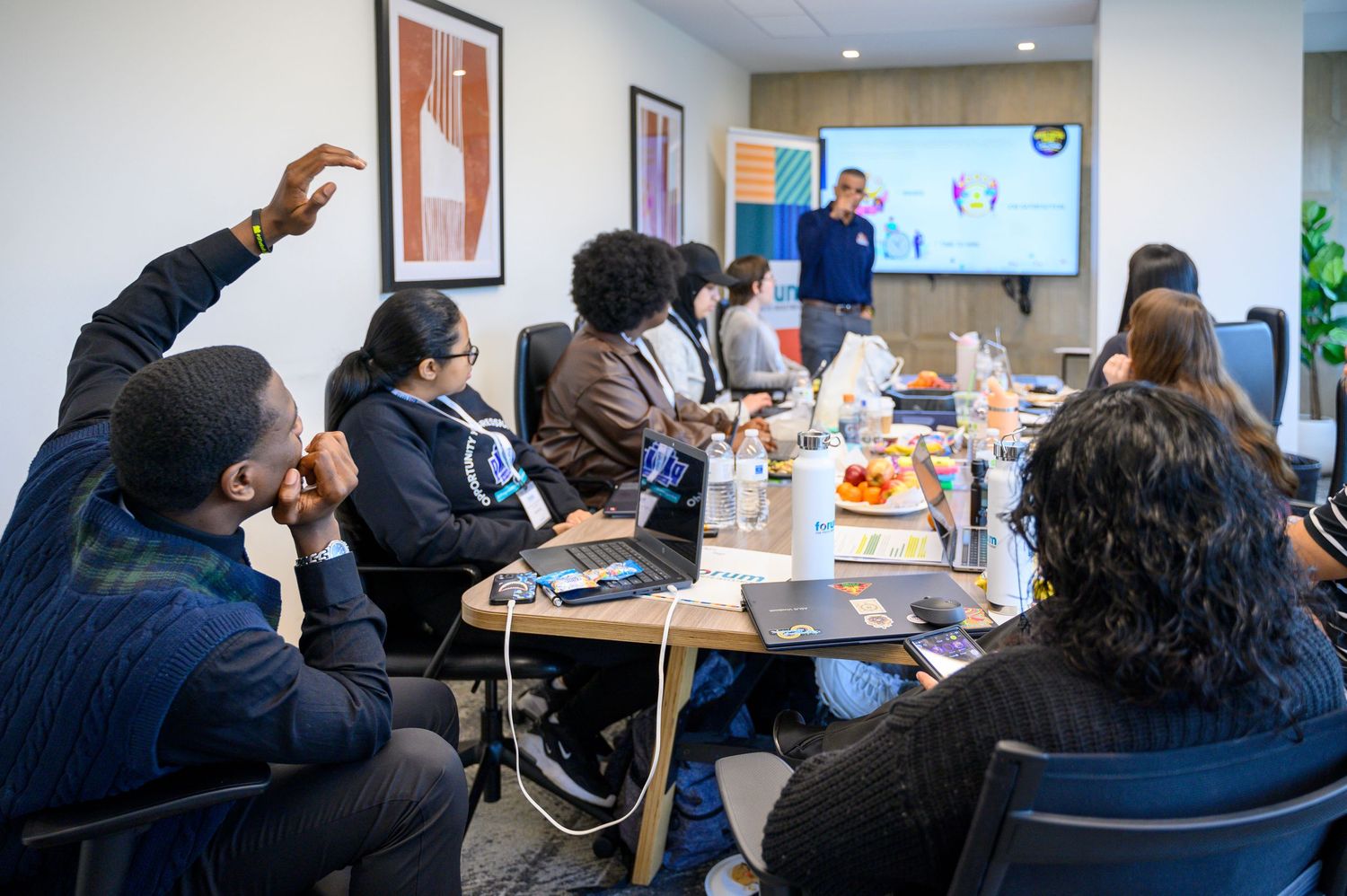 Diverse group of professionals in a modern conference room attending a business presentation with a speaker at the front.