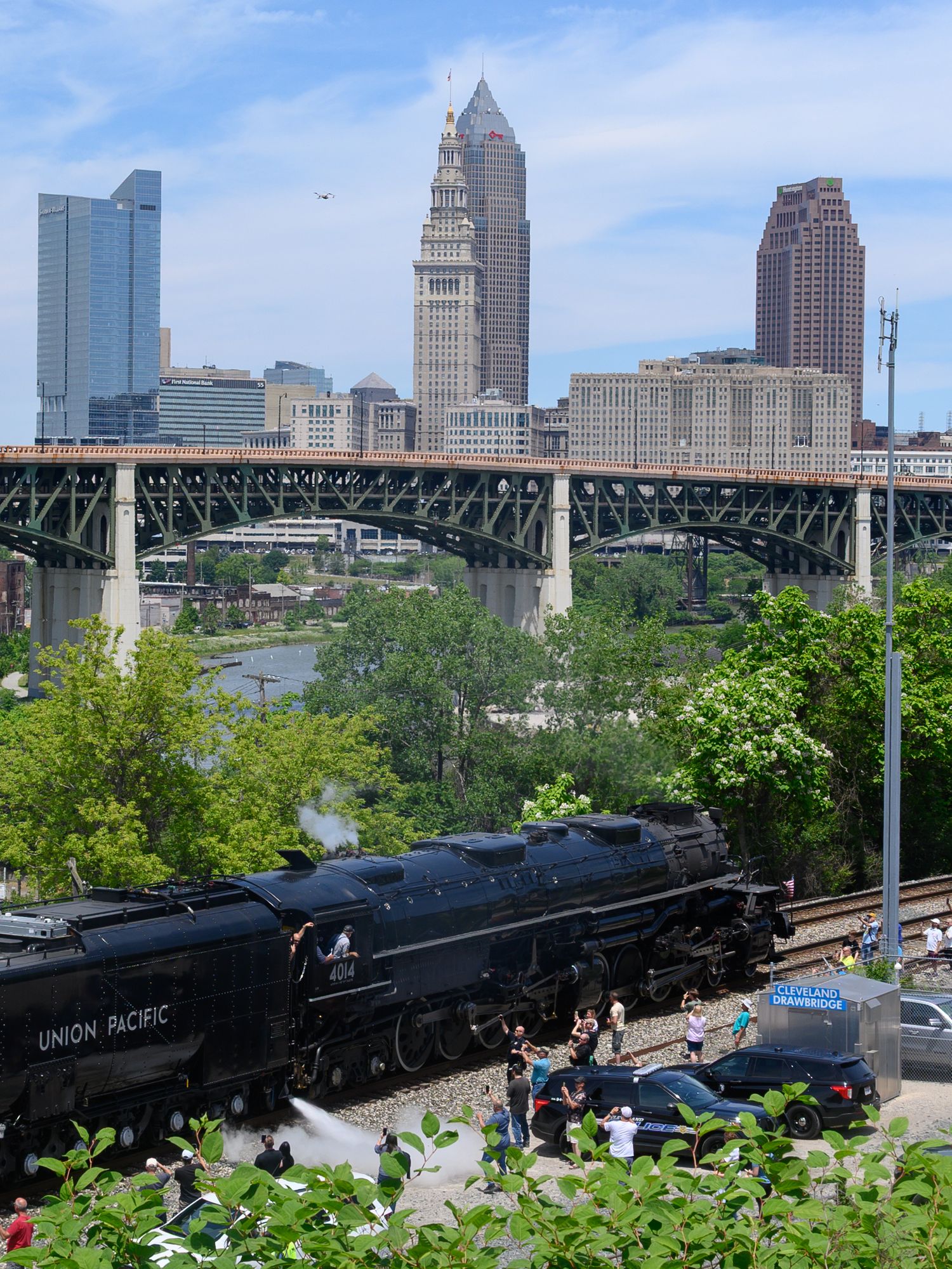 Union Pacific steam locomotive passes through Cleveland Ohio with city skyline and bridge visible in background.