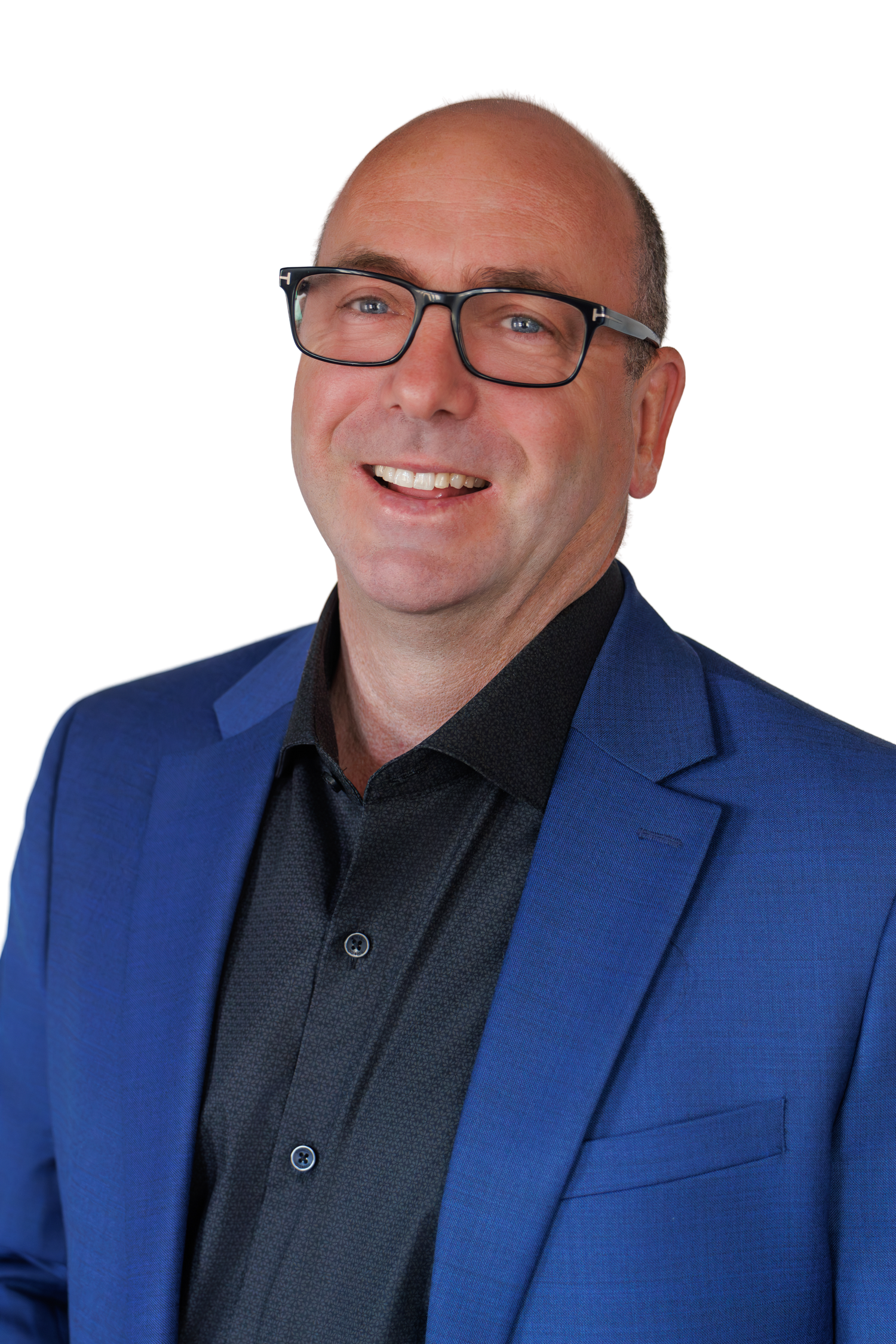Professional bald man in blue blazer and black shirt smiling against a white background.