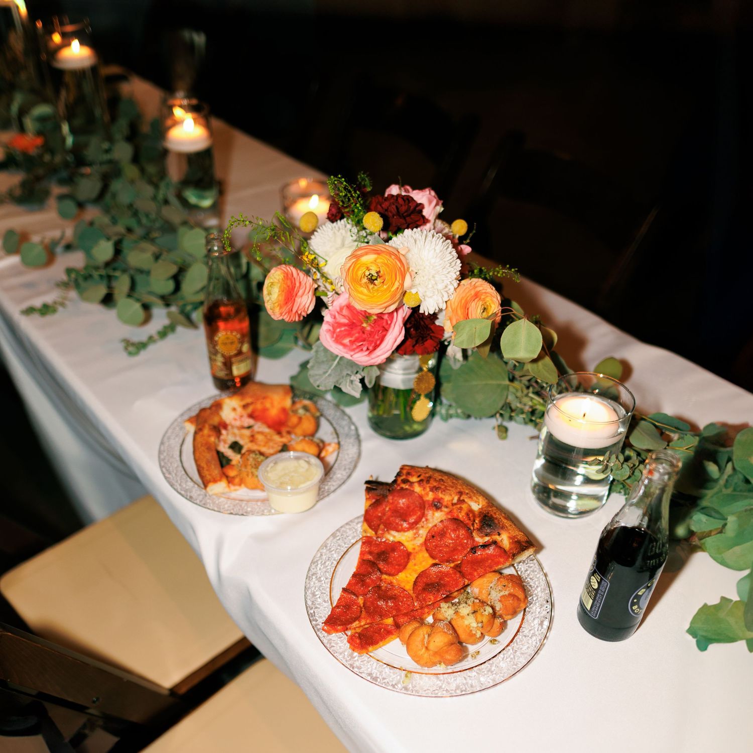 Wedding reception table settings with elegant food presentation and greenery decorations.