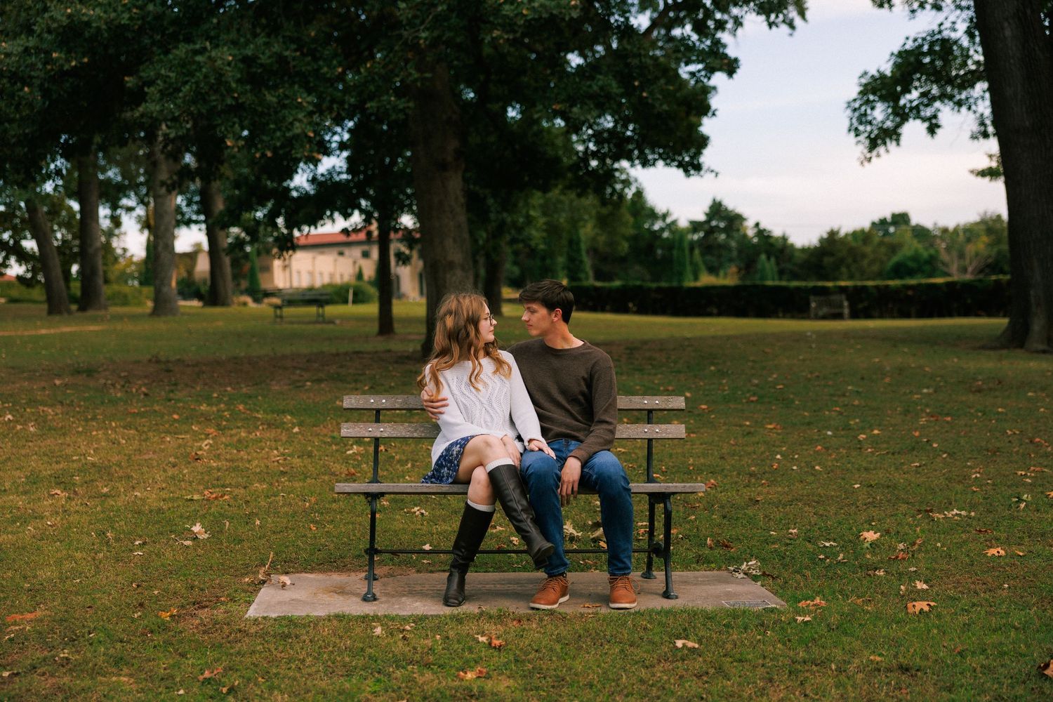 People relaxing in a park with benches and trees on a sunny autumn day.