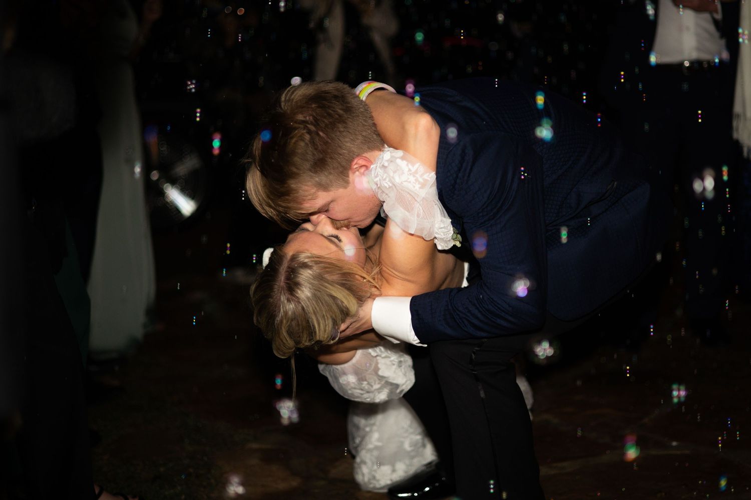 A romantic wedding couple shares intimate dances and embraces in a dimly lit ballroom setting.