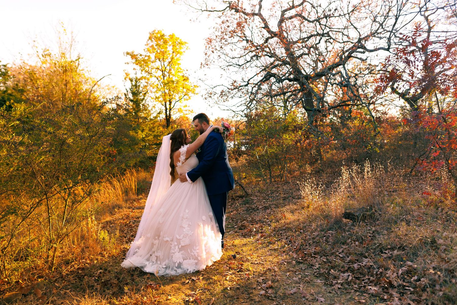 Romantic sunset photo session in autumn with golden light filtering through trees on a hillside.