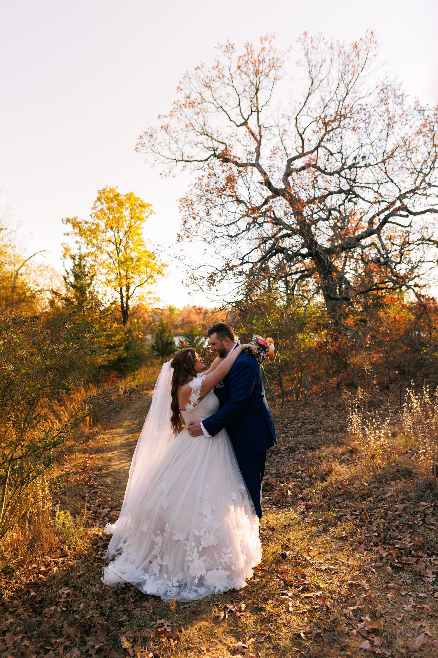 A romantic autumn wedding photoshoot in a golden-lit natural setting with fall foliage.