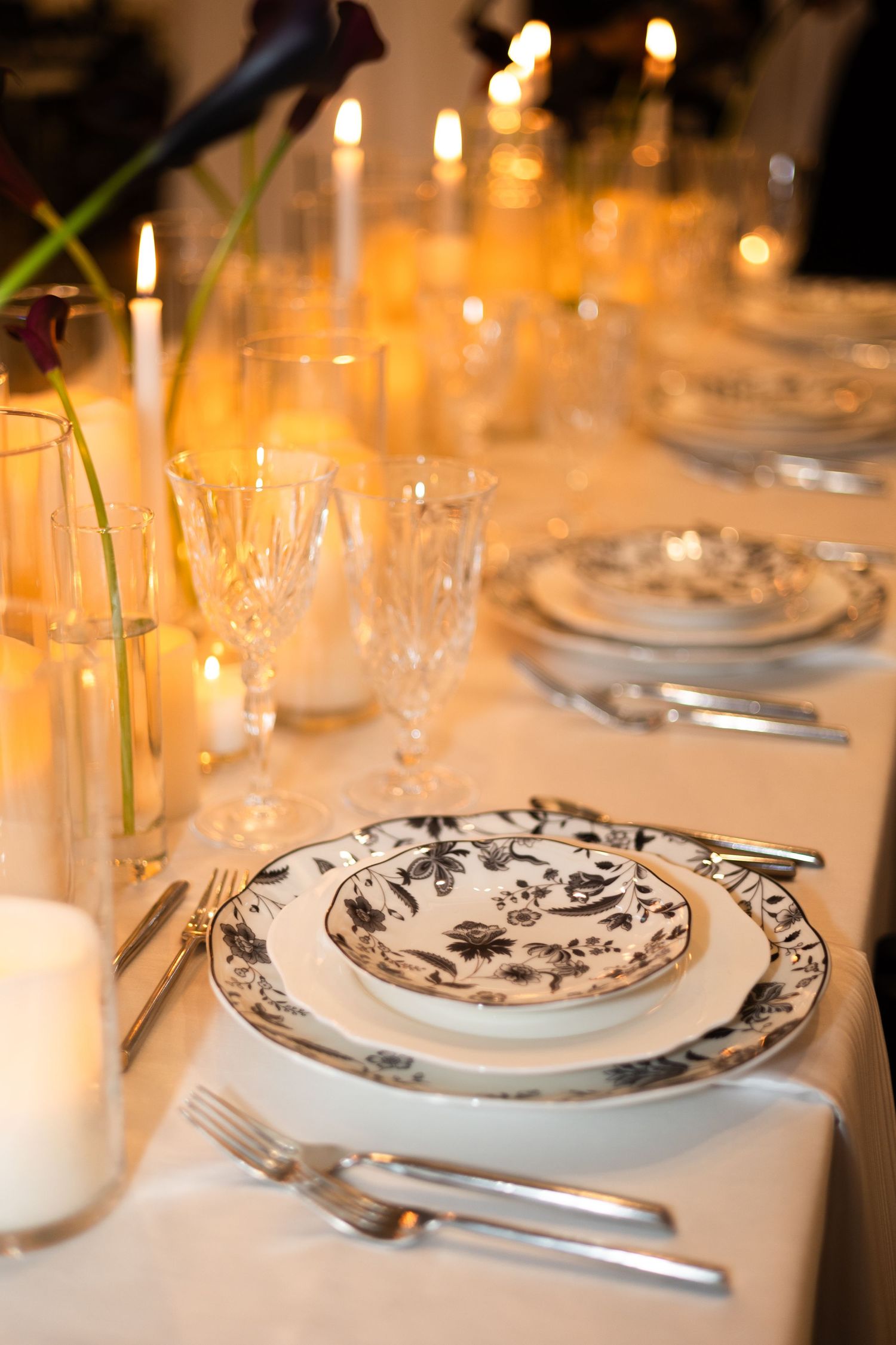 Elegant table settings with black and white patterned plates and glowing candles create a romantic dining atmosphere.