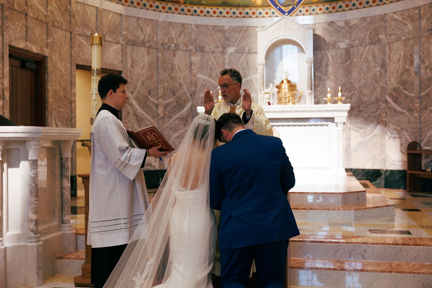 Wedding ceremony taking place in a beautiful church with elegant marble columns and arched ceilings.