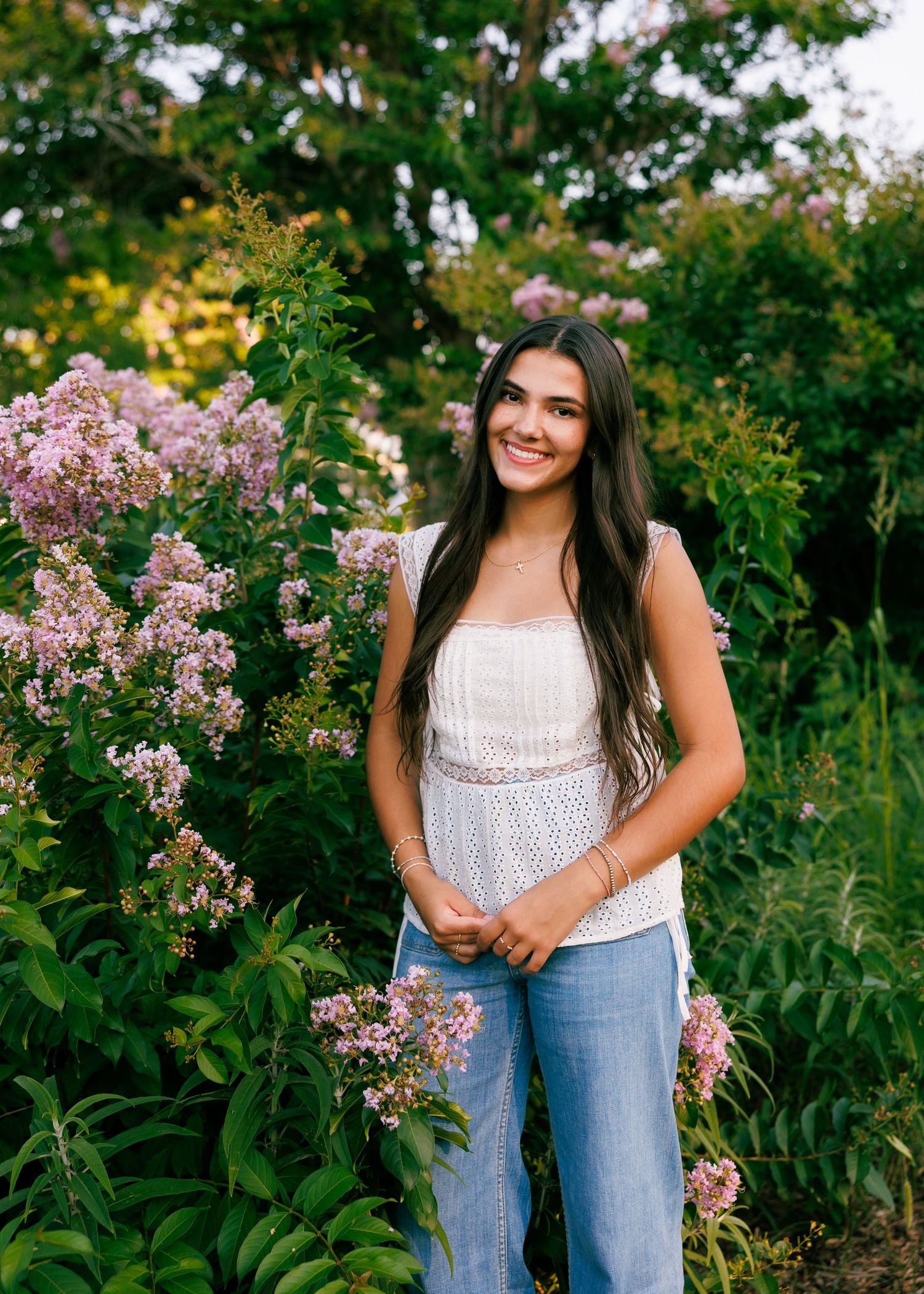 White lace top and blue jeans outfit styled in a blooming flower garden setting.