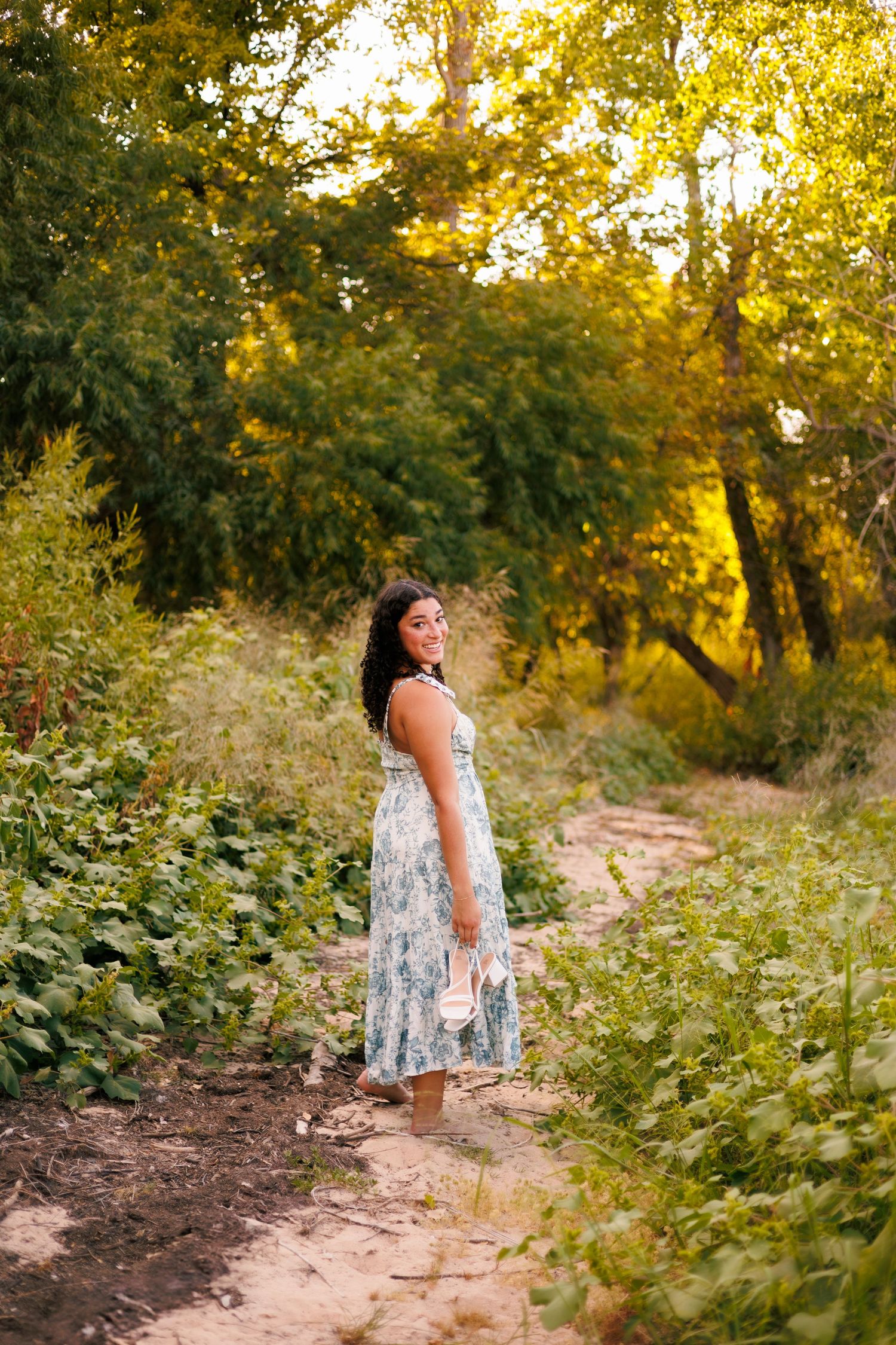 A dreamy outdoor photoshoot in a golden-lit natural setting with wildflowers and greenery.