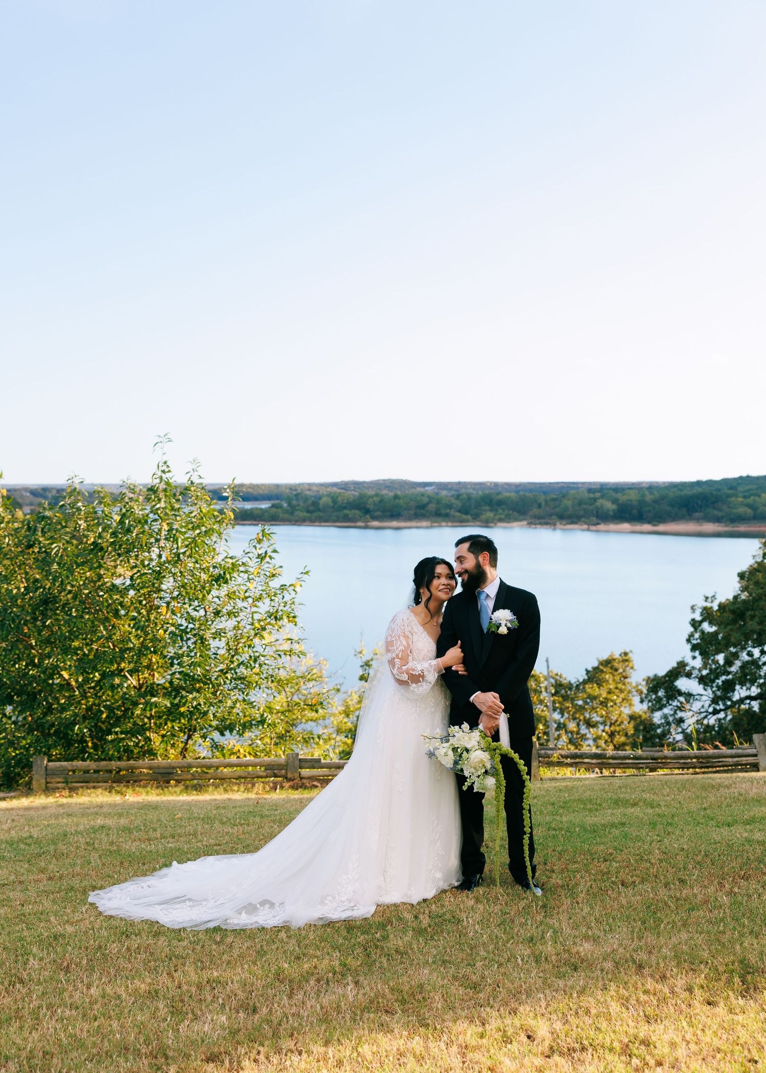 Scenic lakeside wedding portrait with rolling hills in the background.