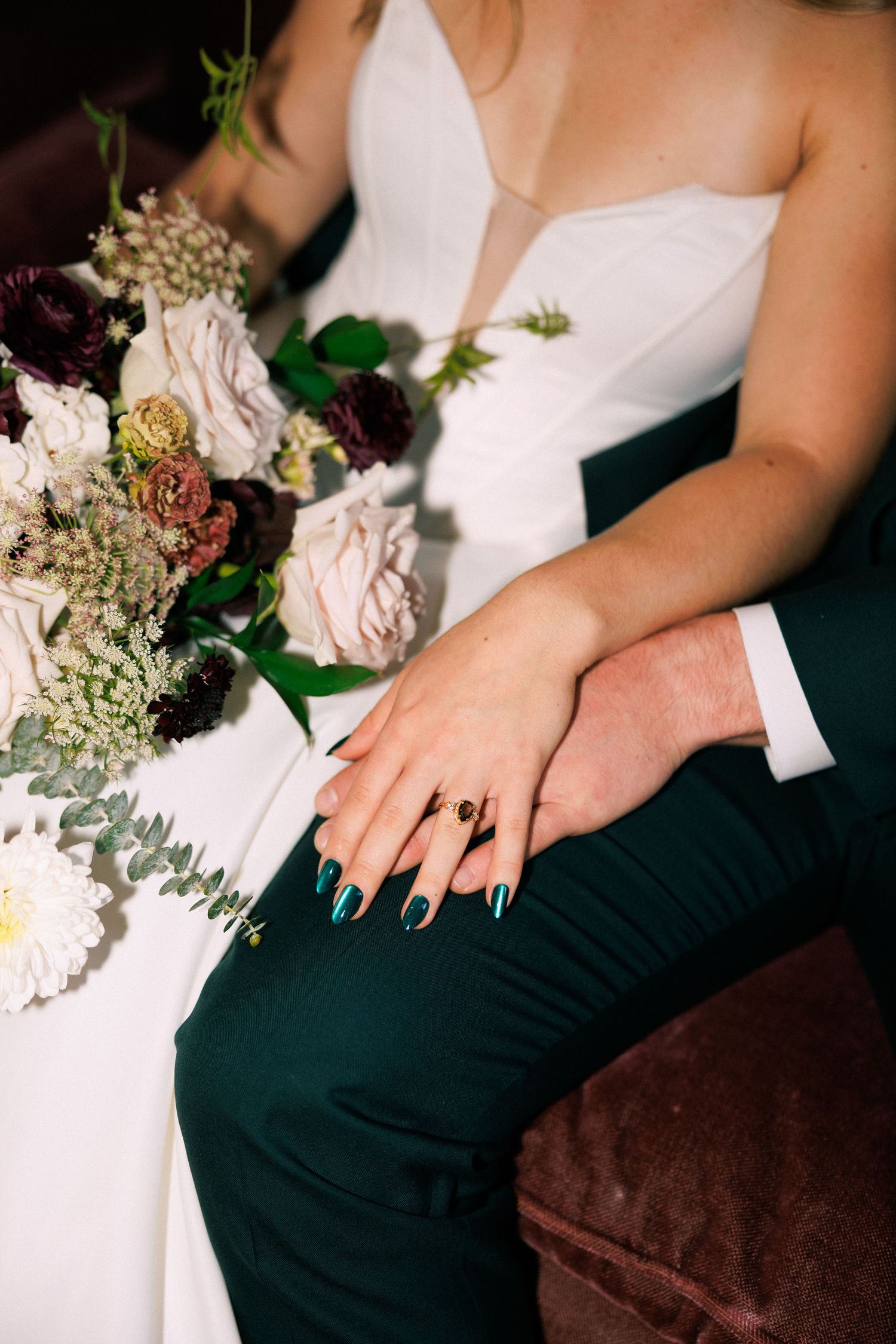 Close-up of white wedding bouquet with roses and greenery next to formal attire.