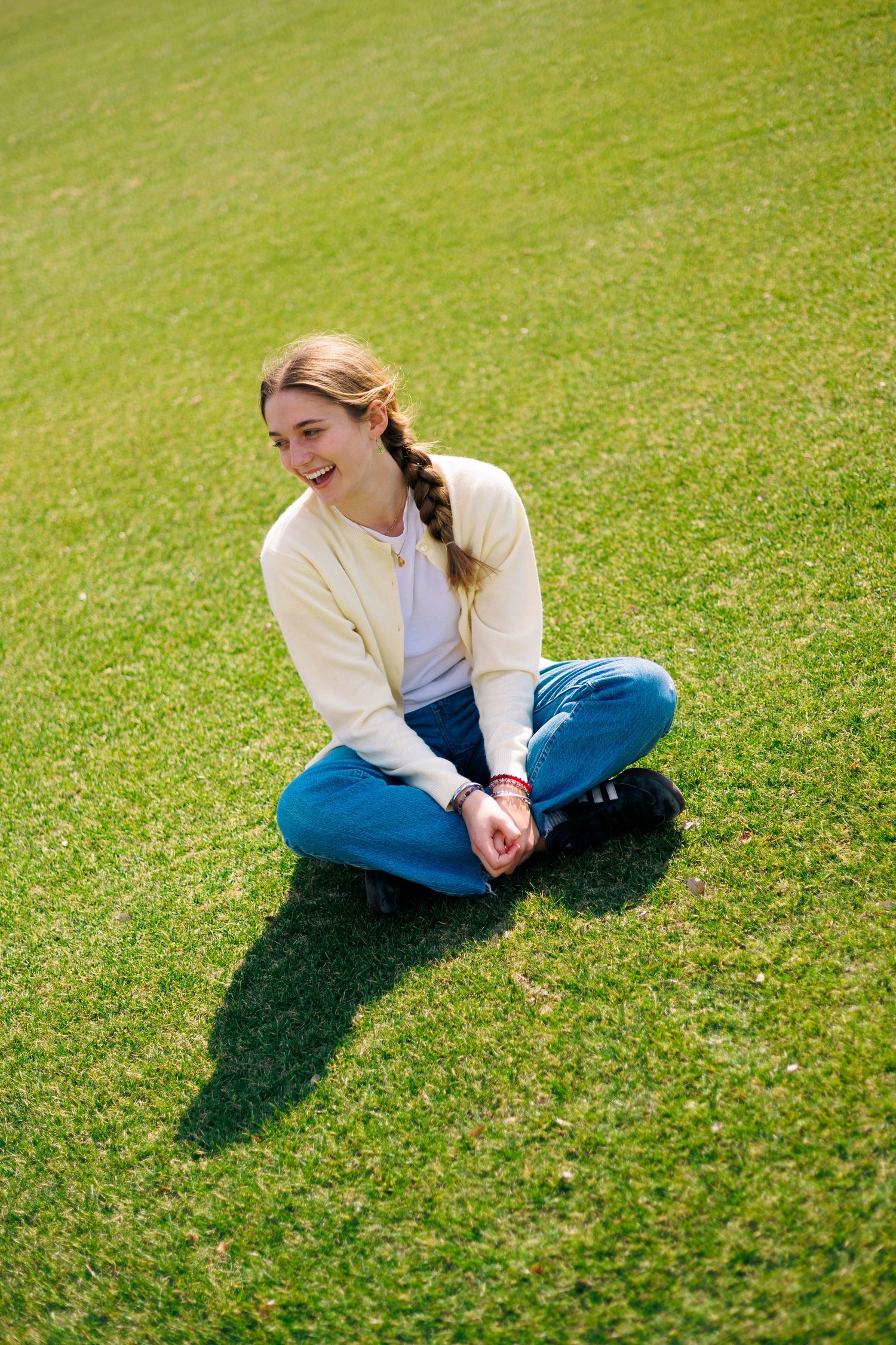 A casual outfit with yellow cardigan and jeans creates a peaceful scene on green grass.