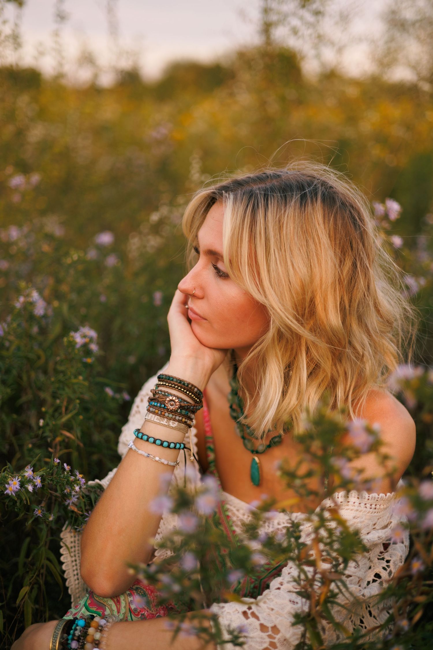Artistic portrait in a wildflower meadow at golden hour with bohemian jewelry and styling.