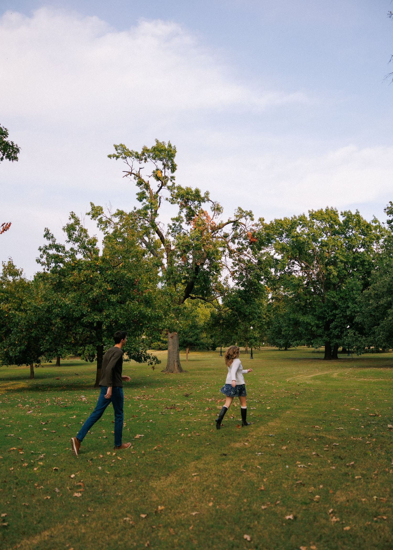 People playing and flying kites in a grassy field on an autumn day.