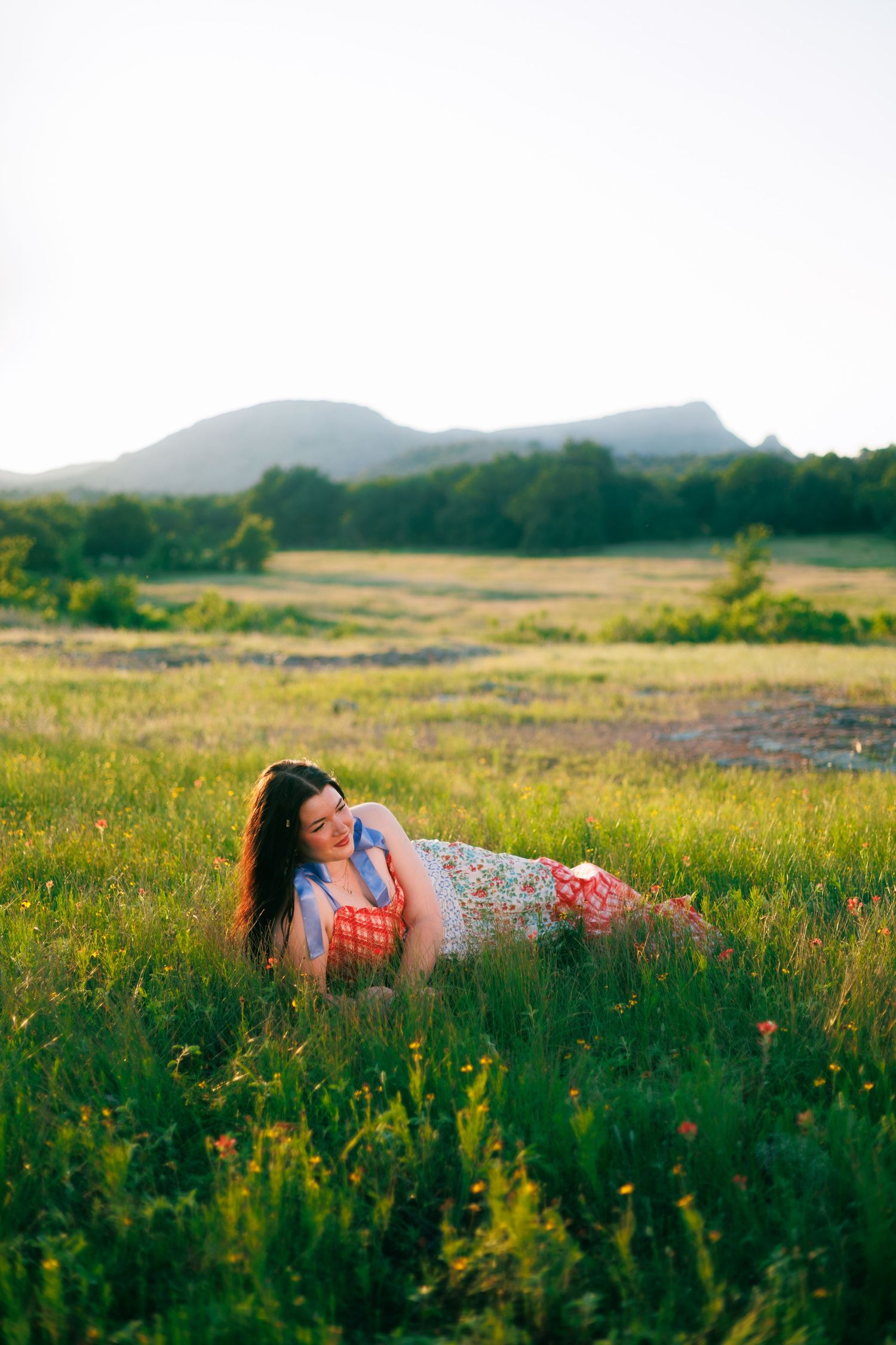 A dreamy photoshoot in a wildflower meadow with mountains visible in the background at golden hour.