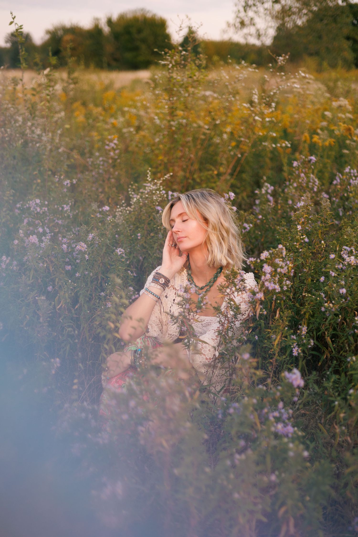 Dreamy wildflower field portrait with soft lighting and purple flowers.