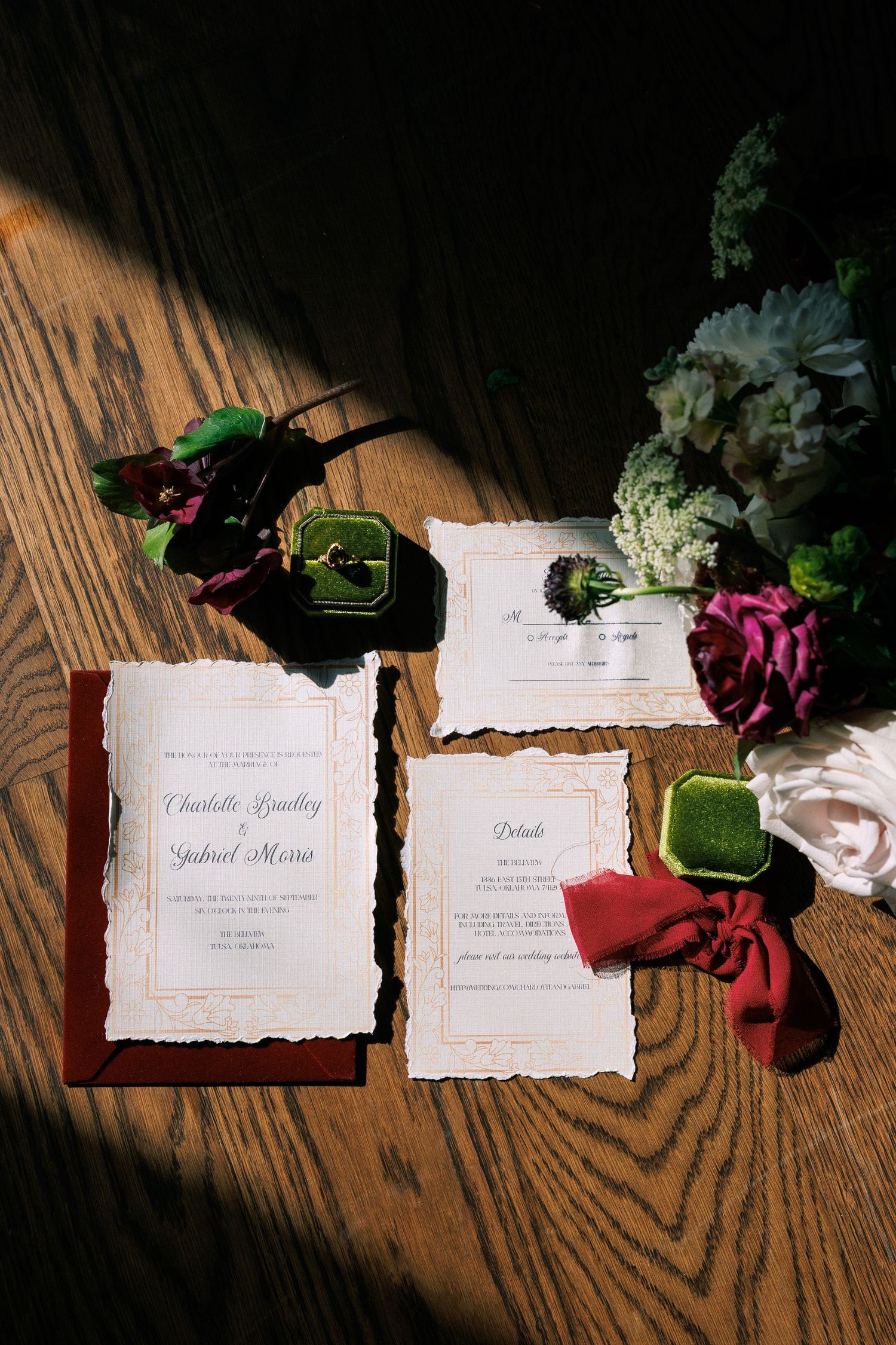 Wedding invitation suite with deckled edges and floral accents photographed on wooden surface.