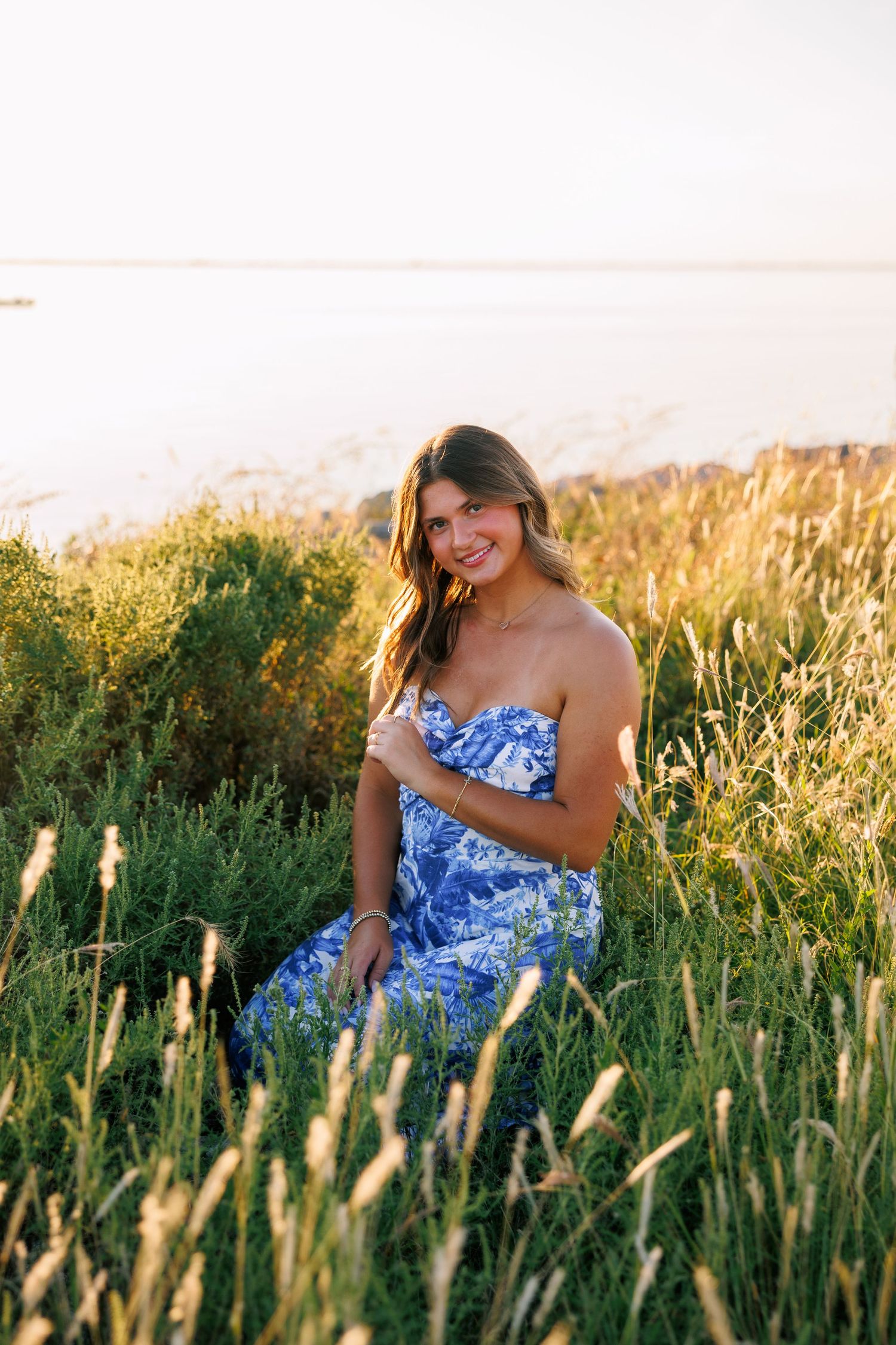 Golden sunlight illuminates tall grass as a blue floral dress creates a dreamy summer scene.