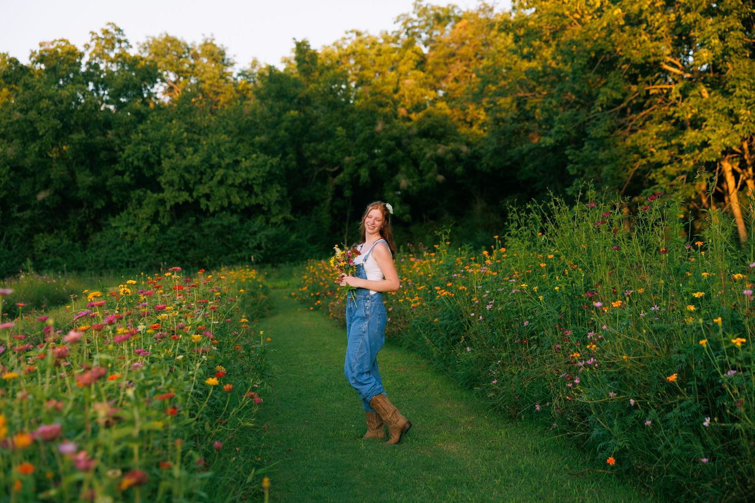 Figure in blue jeans dances along a garden path lined with colorful summer wildflowers.