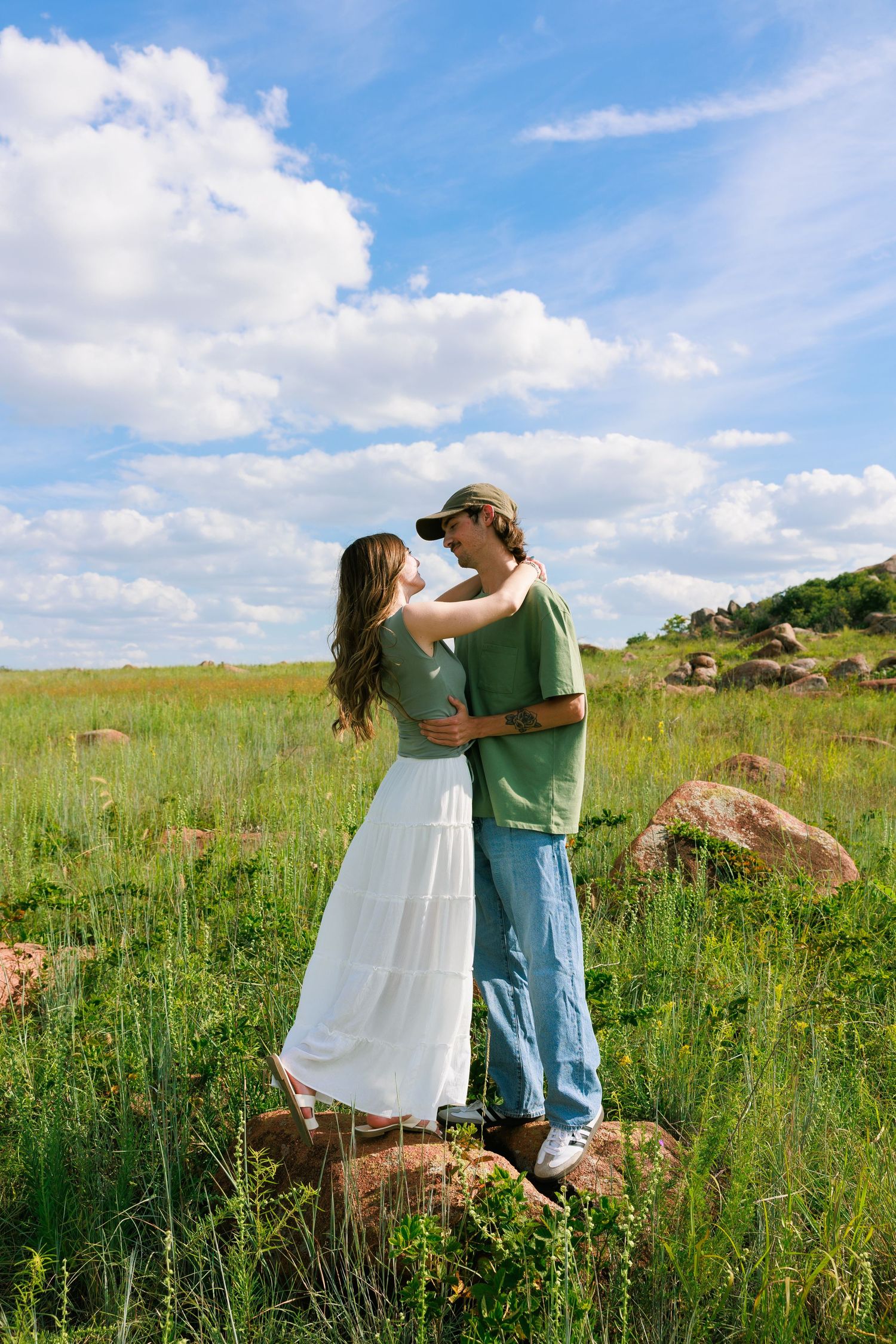 Couple embracing in a wildflower meadow under bright blue summer skies.