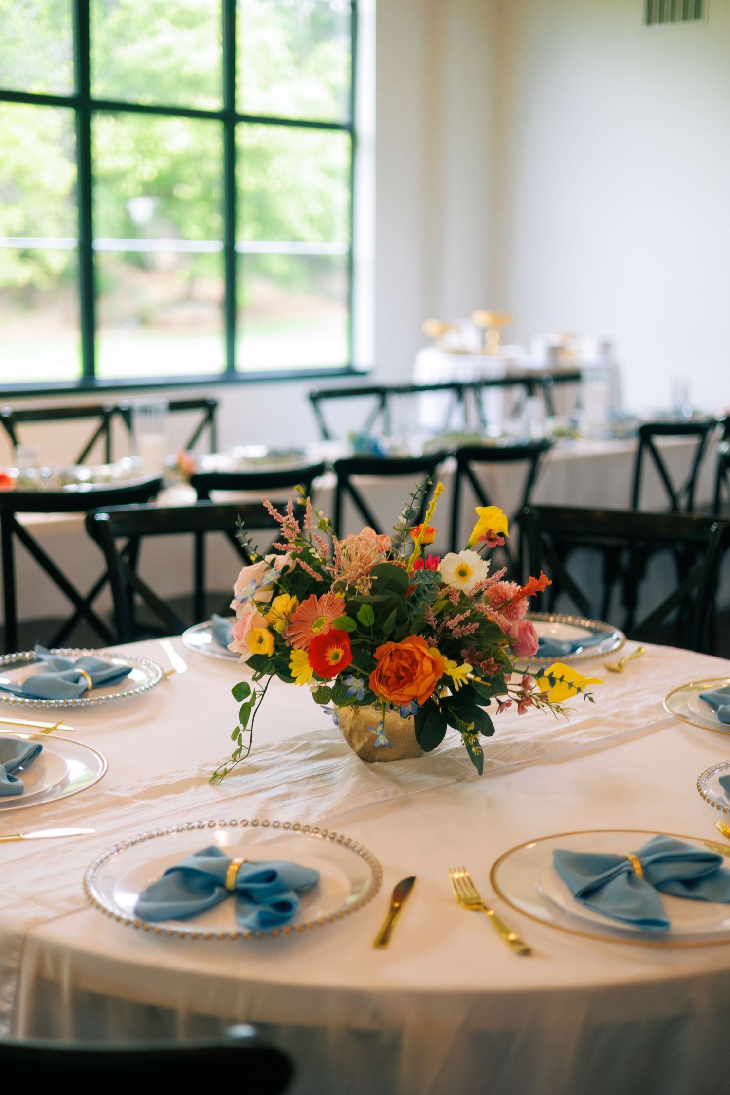 Elegant wedding reception tables set with floral centerpieces and blue accents.