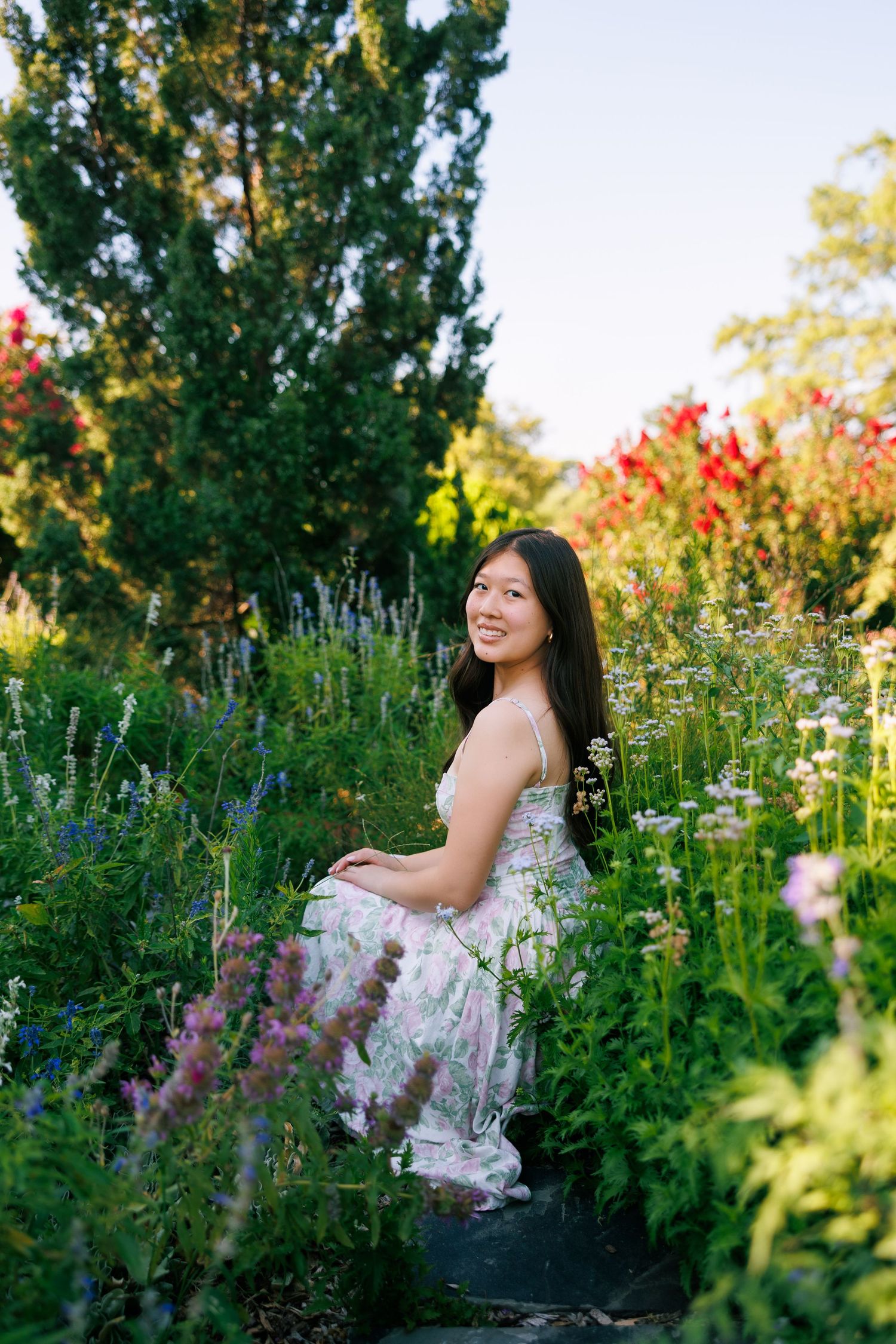 A floral dress harmonizes with wildflowers and greenery in a summer garden.