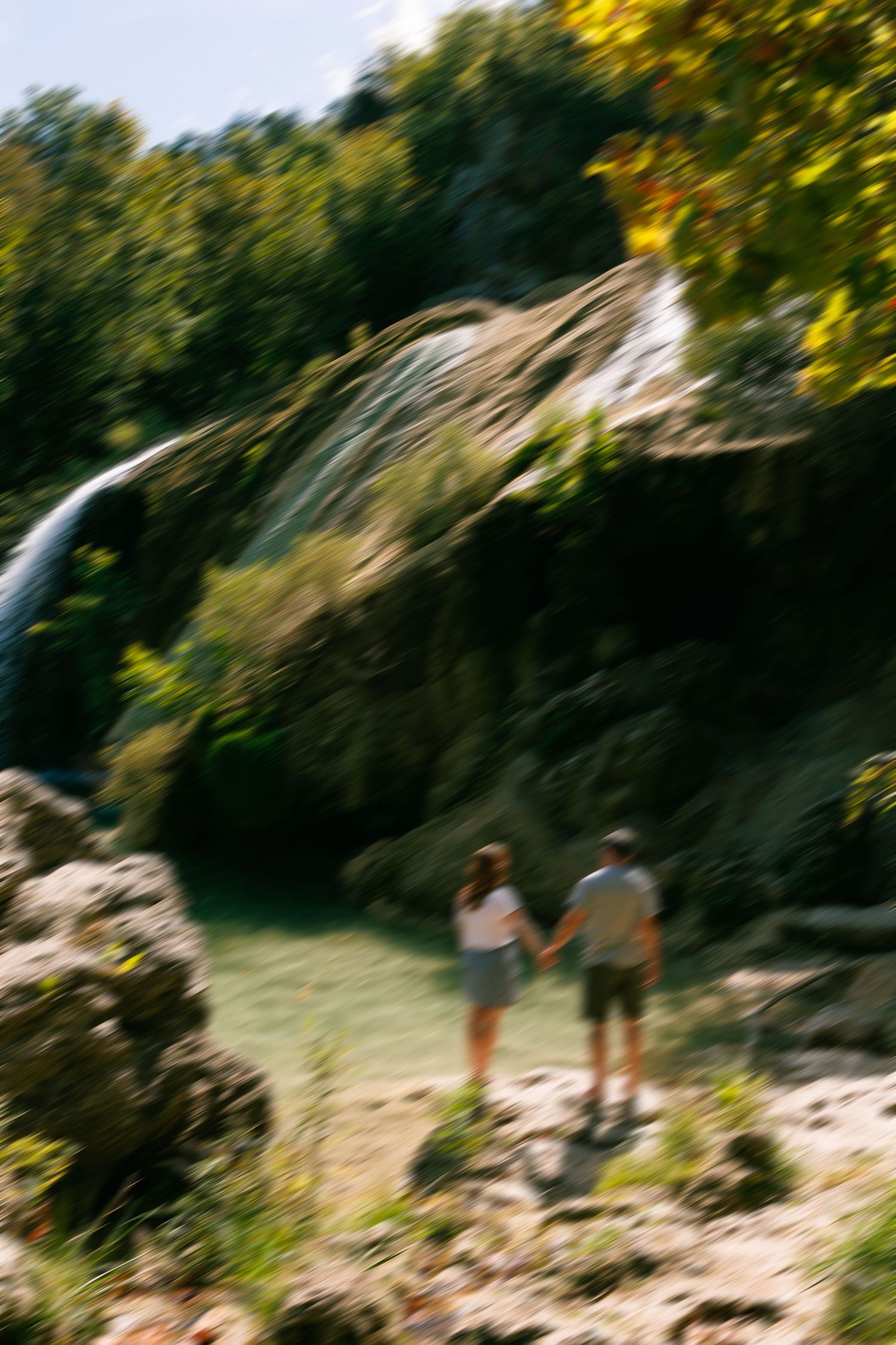 Blurred motion photograph of people walking near trees in bright sunlight.