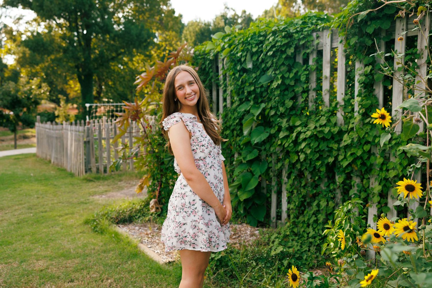 A floral sundress in a garden setting with climbing vines and sunflowers.