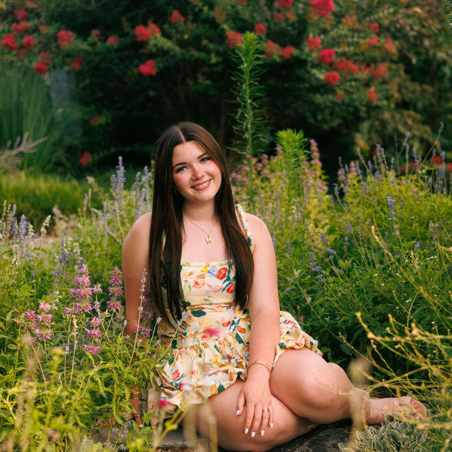 Summer garden portrait session with floral dress amid colorful blooms.