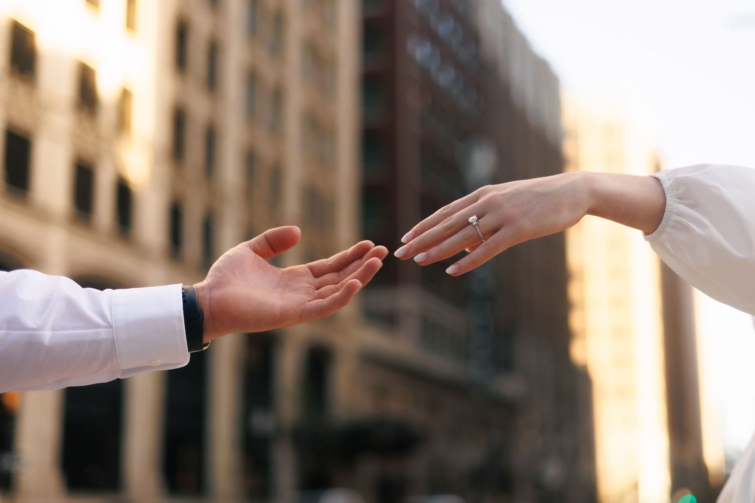 Close-up of hands reaching toward each other in warm sunlight.