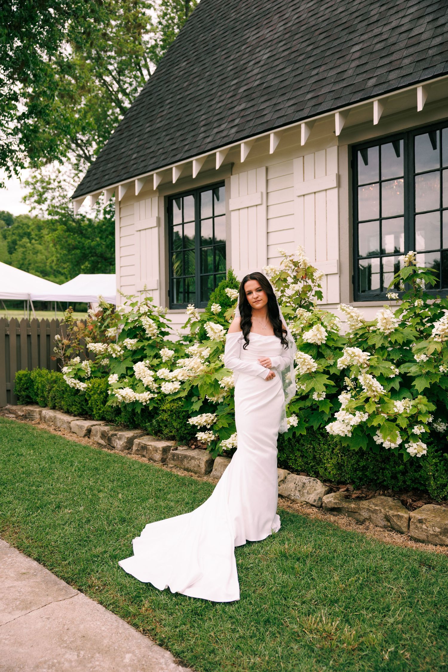 White farmhouse-style venue with black trim windows and blooming garden landscaping.