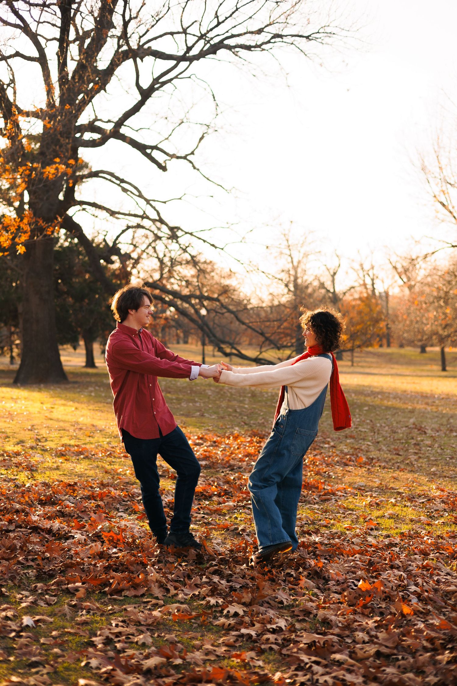Playful autumn photoshoot with people playing in fallen leaves at sunset.