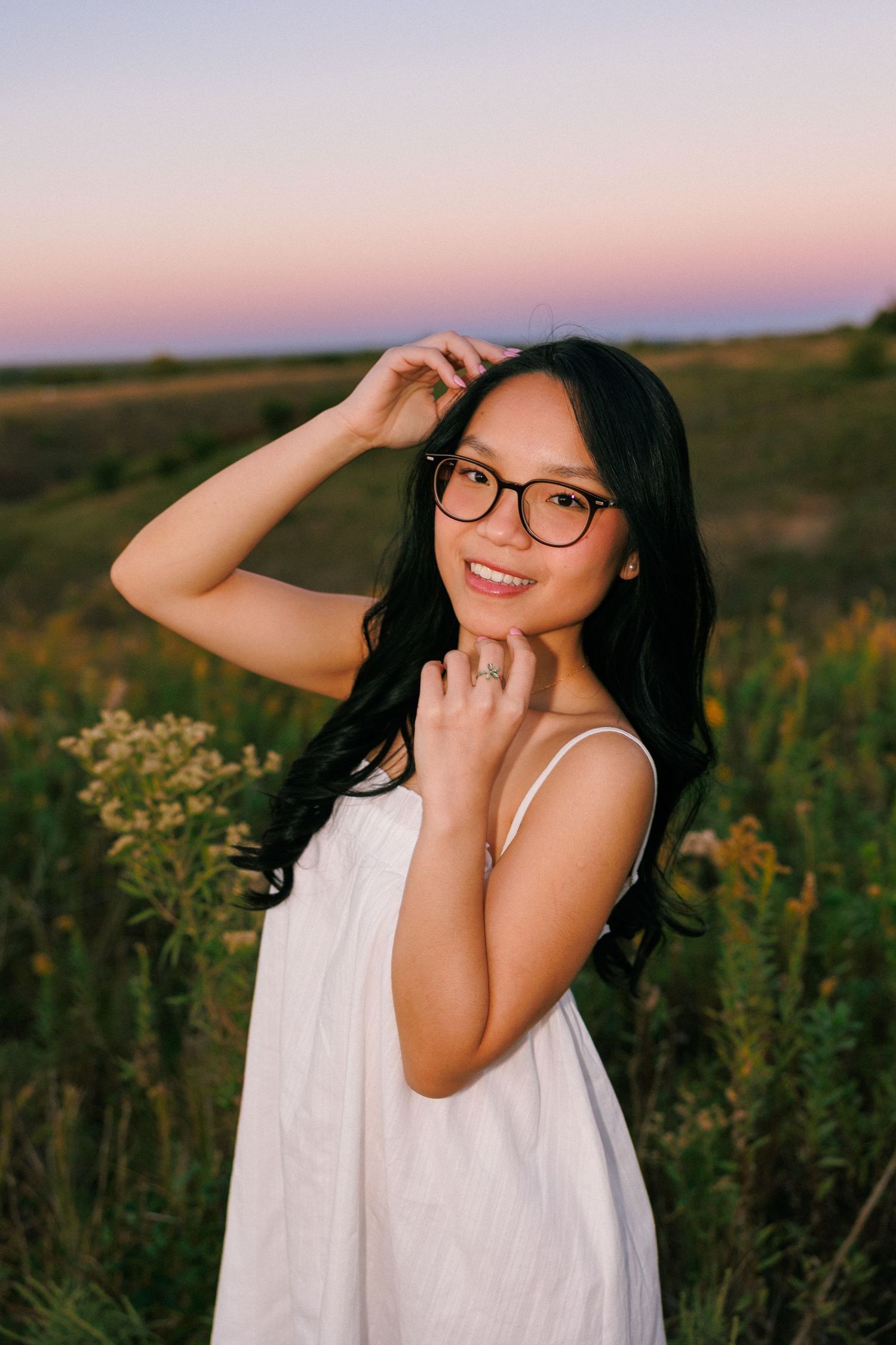 Outdoor portrait session in a field at sunset with soft lighting and natural wildflowers.