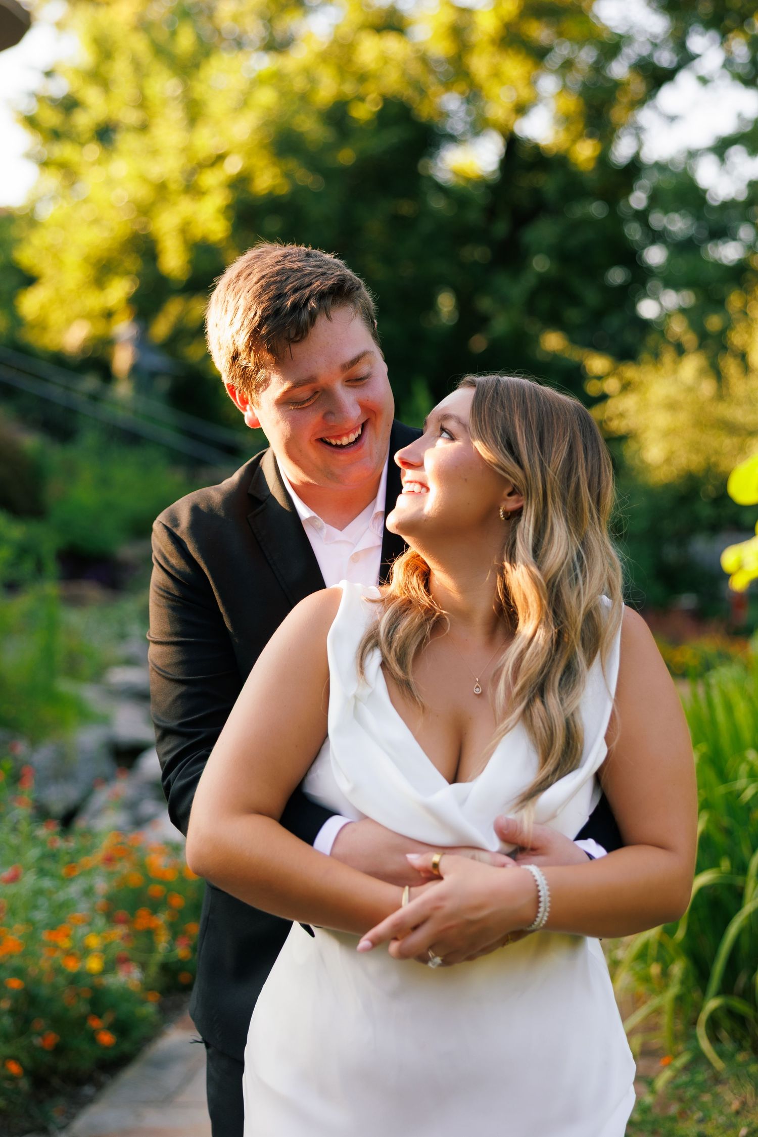A couple shares joyful moments in a garden setting during golden hour.