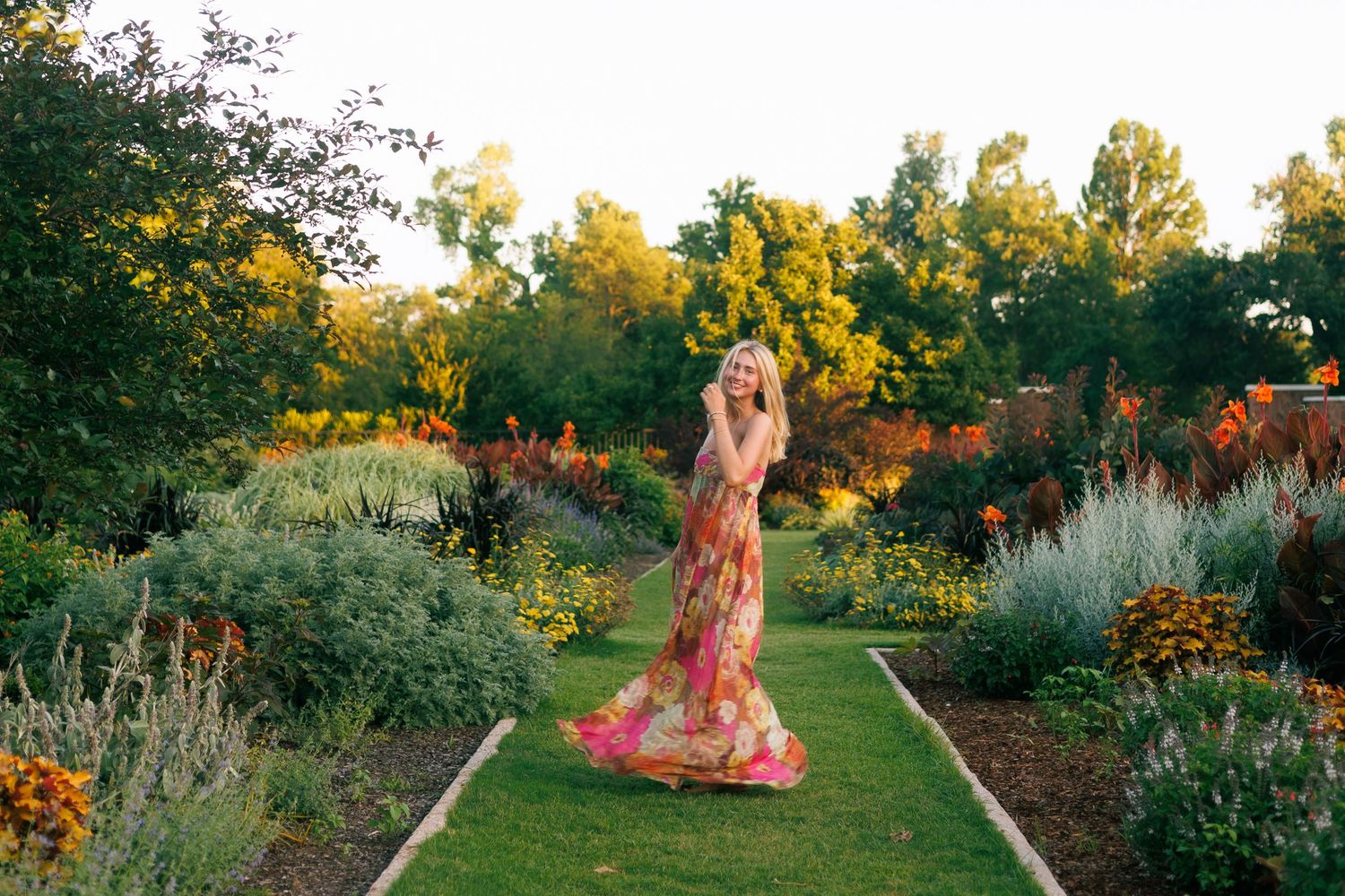 Summer senior photos in a vibrant garden with colorful flowers and winding paths.