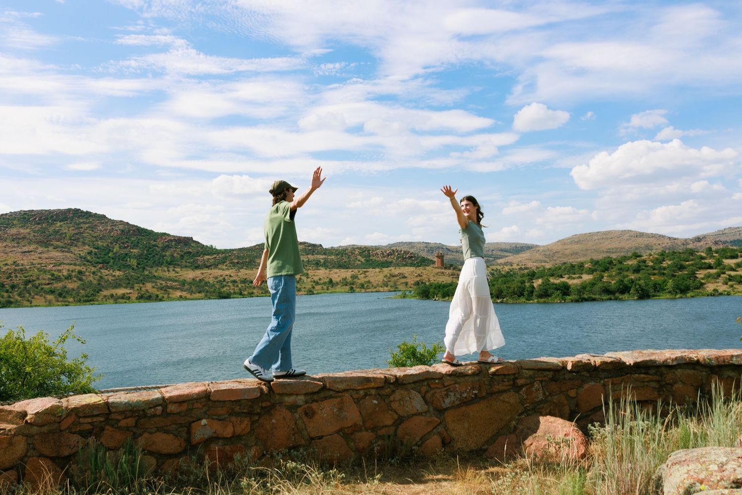 Scenic mountain lake view with people enjoying the peaceful landscape from a stone wall.