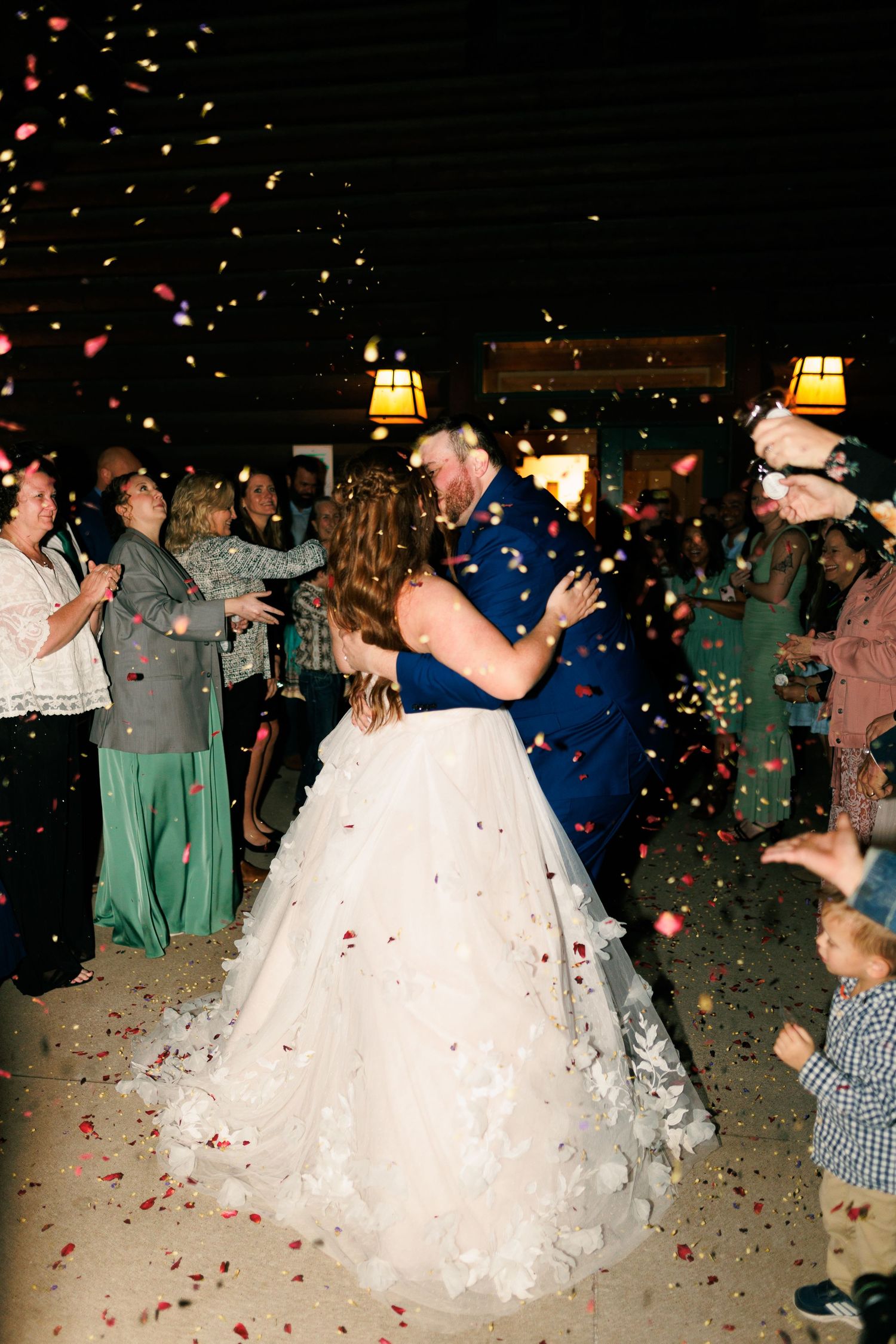 Wedding reception dance floor scene with rose petals falling and guests celebrating.
