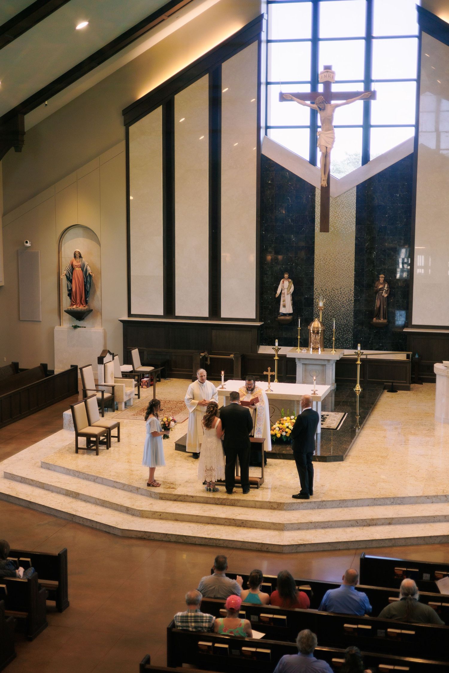 Modern church interior with large windows and cross during a wedding ceremony.