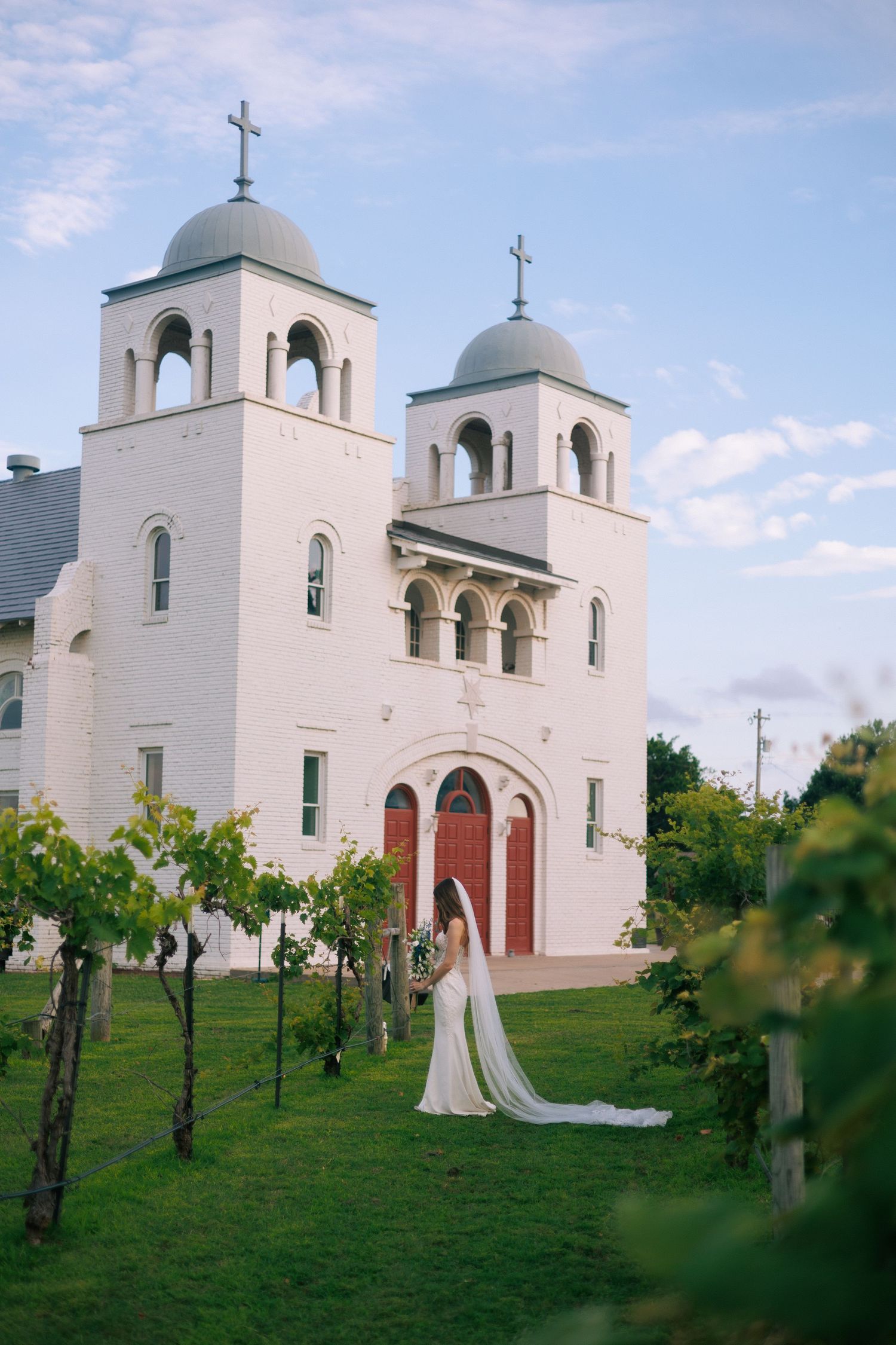A stunning white mission church with twin bell towers sits atop a grassy hill.