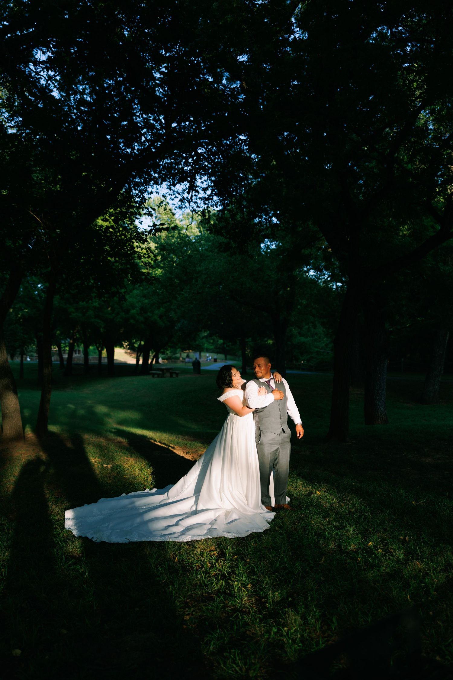 A couple shares intimate wedding photos in a dramatically lit wooded setting.