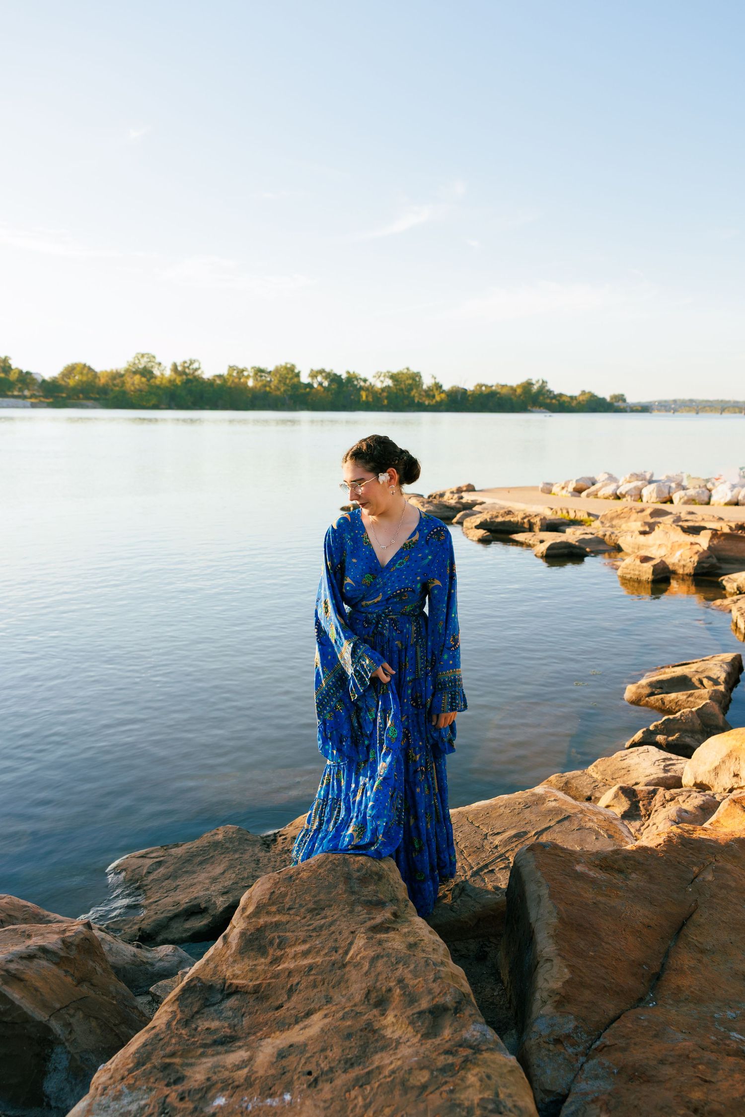 Blue dress portraits on rocky shoreline with calm water and sunset views.