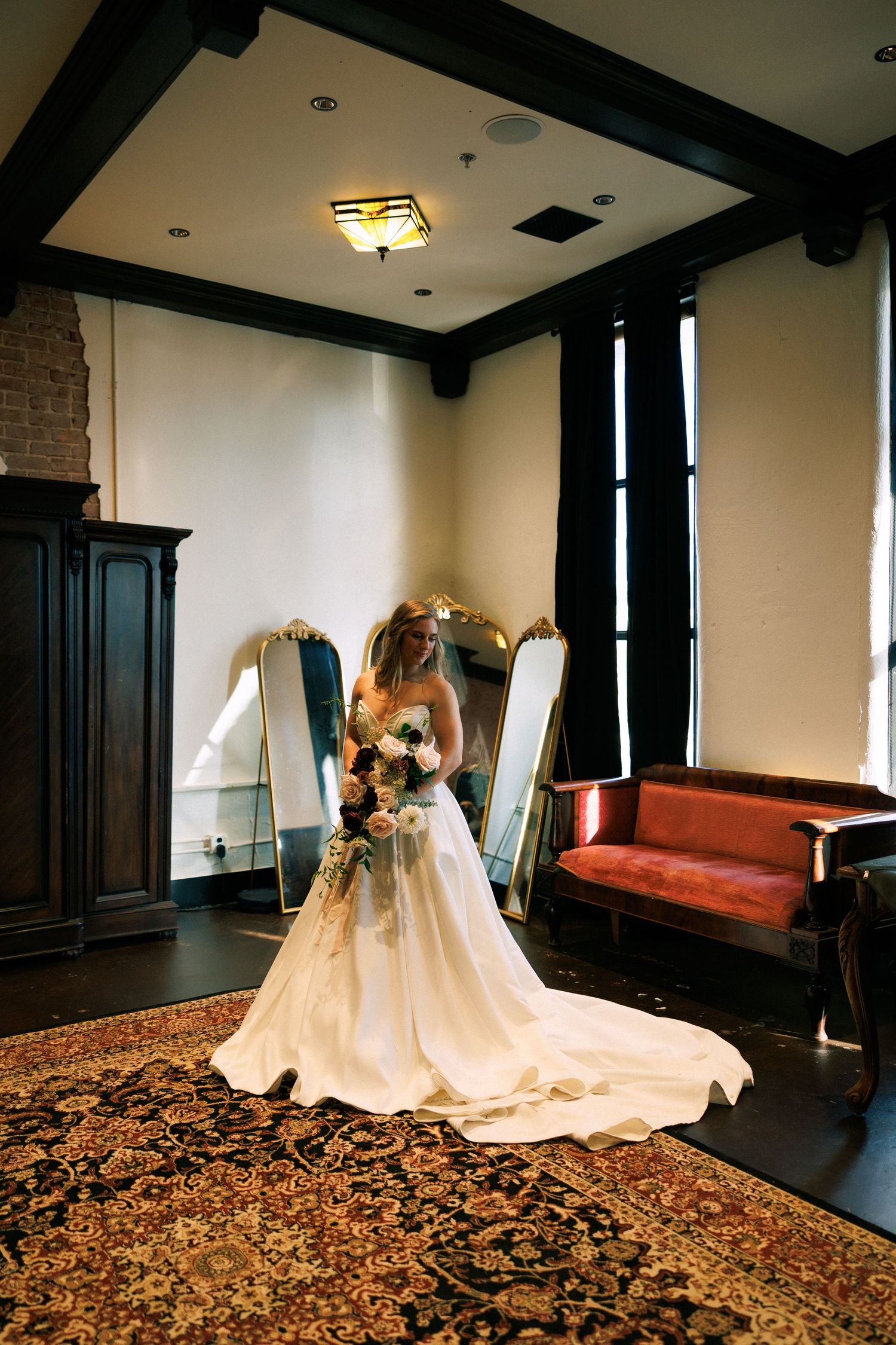 Interior wedding photography session in an elegant room with dark wood trim and ornate carpeting.