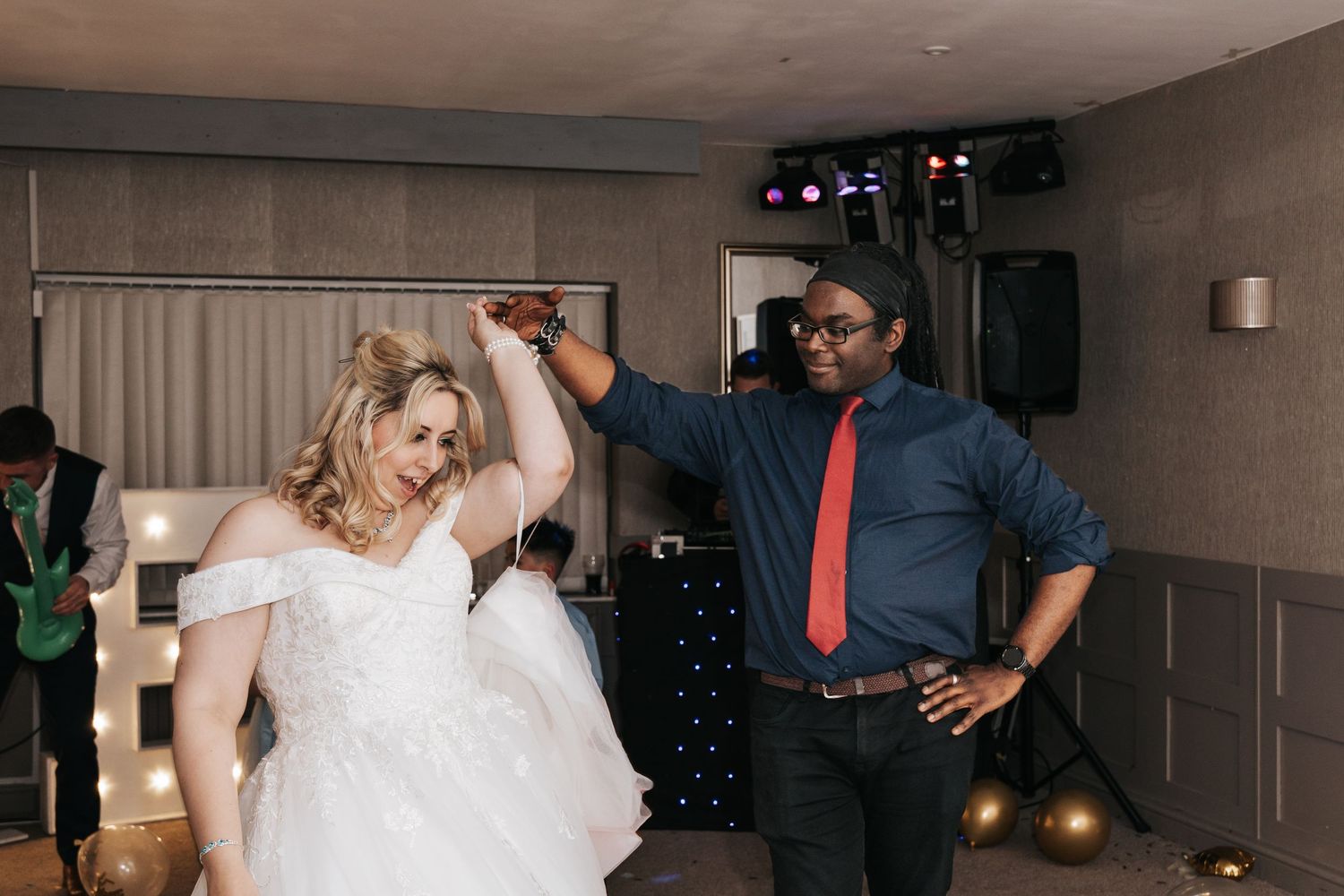 Wedding reception dance floor scene with guests enjoying the celebration in an indoor venue.
