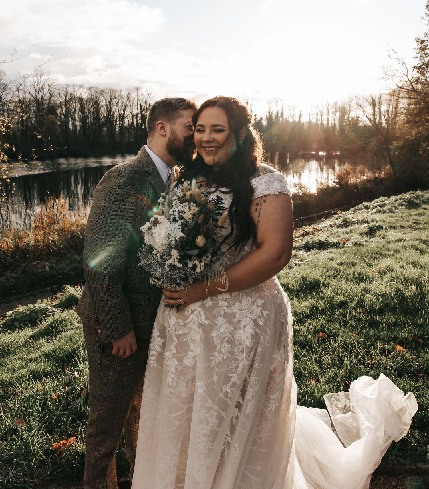 Newlyweds sharing intimate moments during sunset photoshoot in natural outdoor setting.