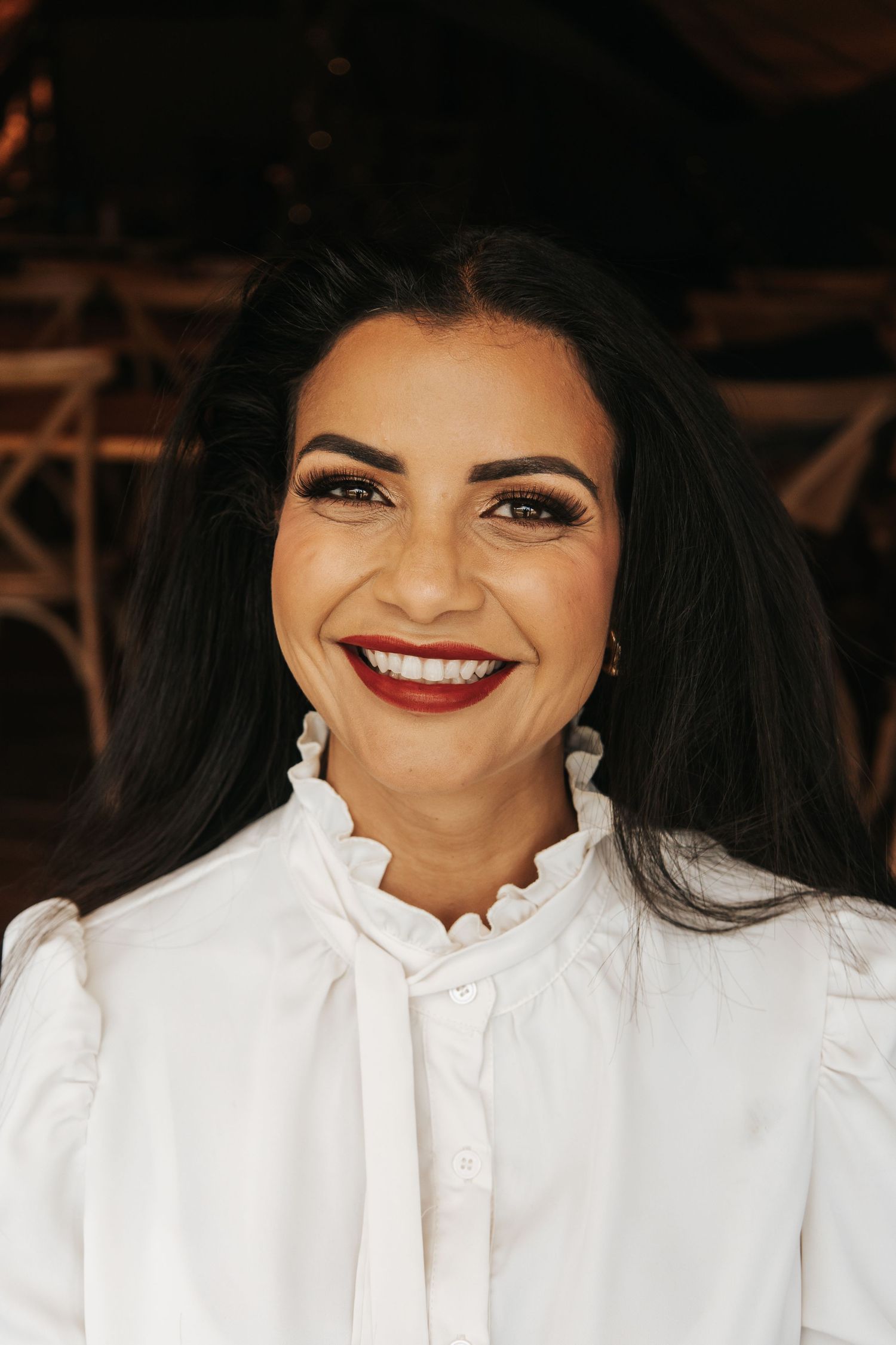 Close-up portrait of someone wearing a crisp white high-neck blouse with a bright smile.