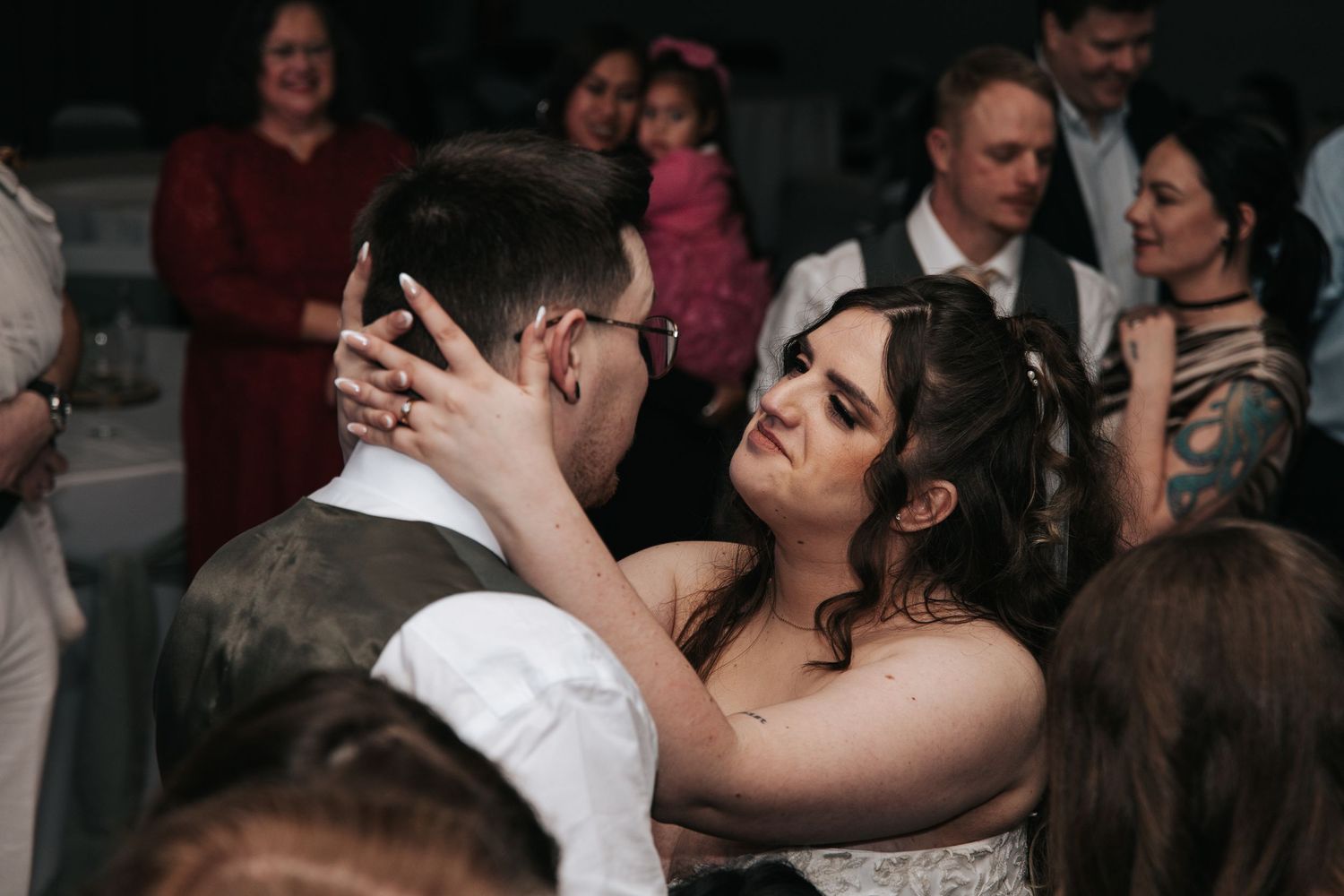 A couple shares an intimate dance moment at their wedding reception while guests look on in the background.