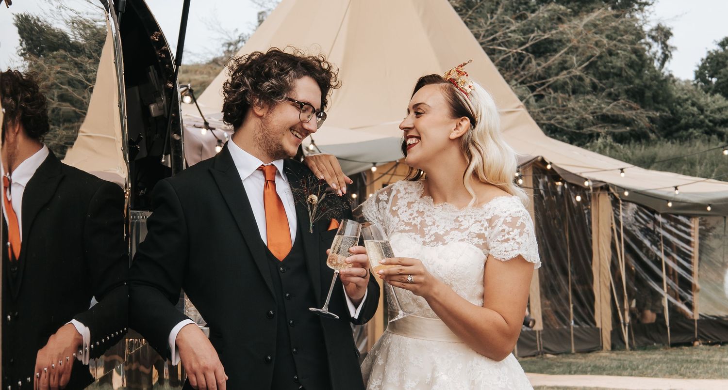 A joyful wedding celebration moment captured outdoors under a white tent canopy.