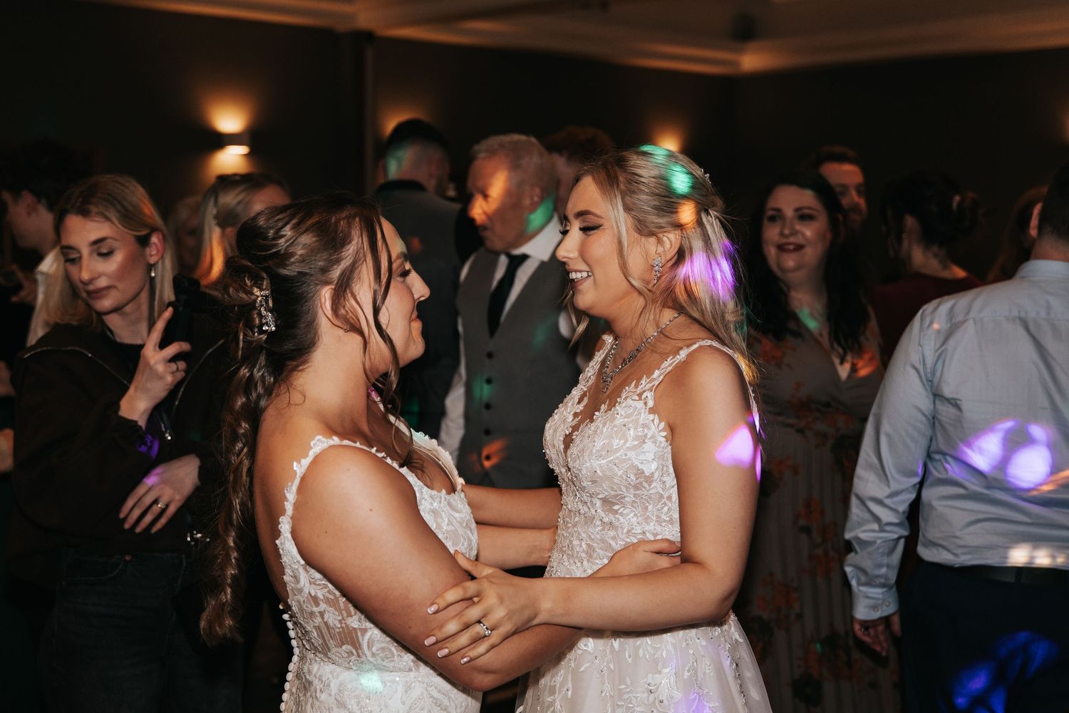 Two people dance together during a wedding reception celebration on a dimly lit dance floor.